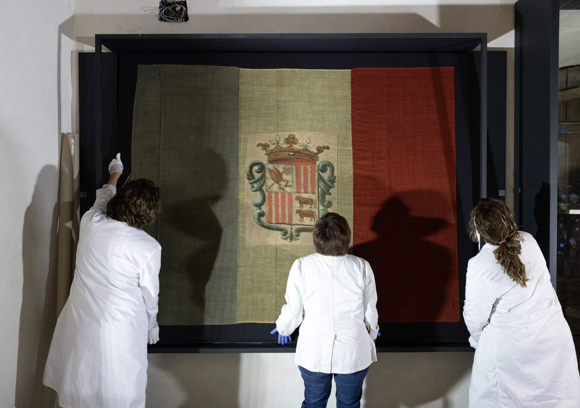 L’equip de restauració col·loca la bandera a la vitrina de la Casa de la Vall.