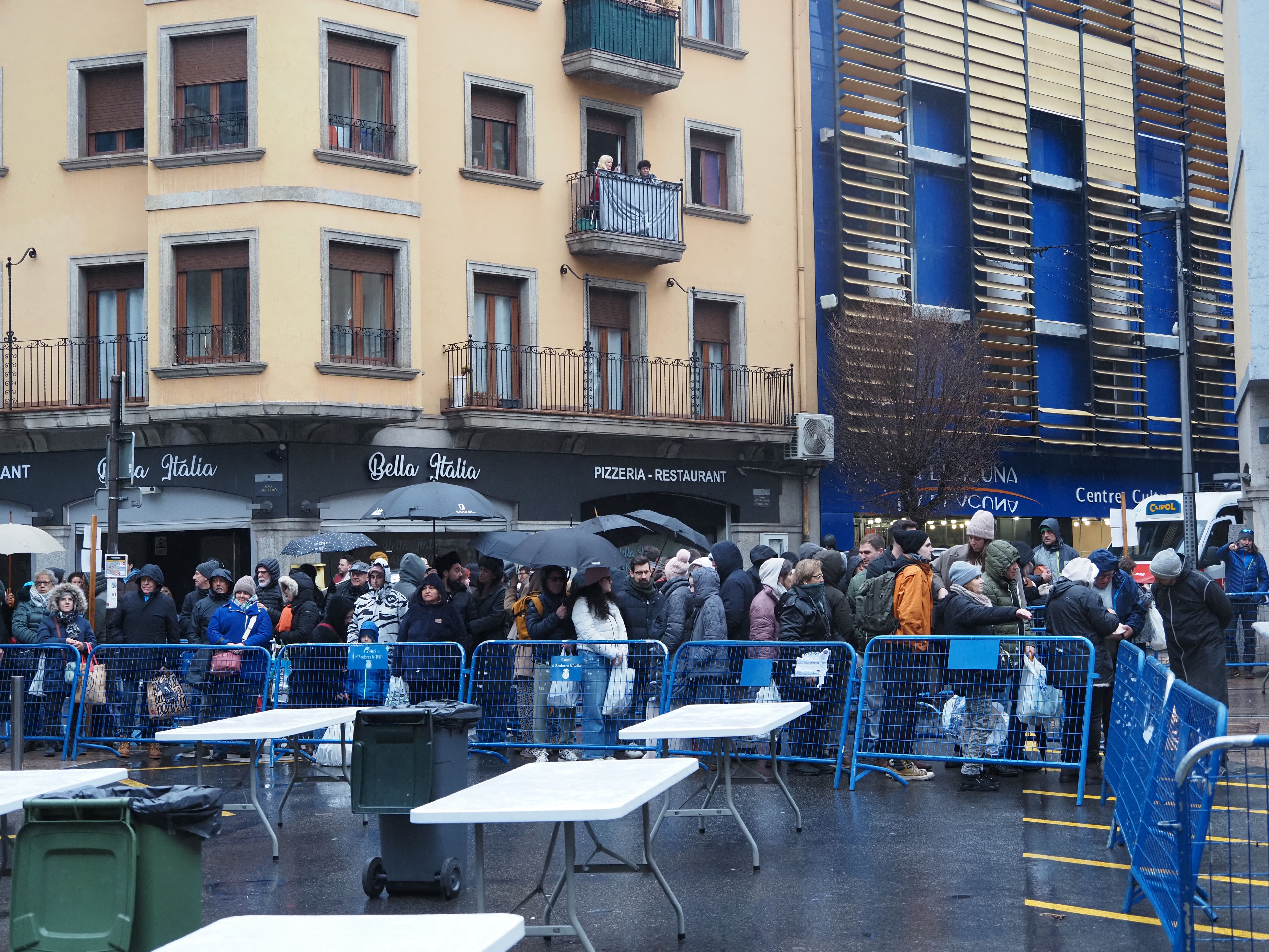 La gent fent cua sota la pluja.