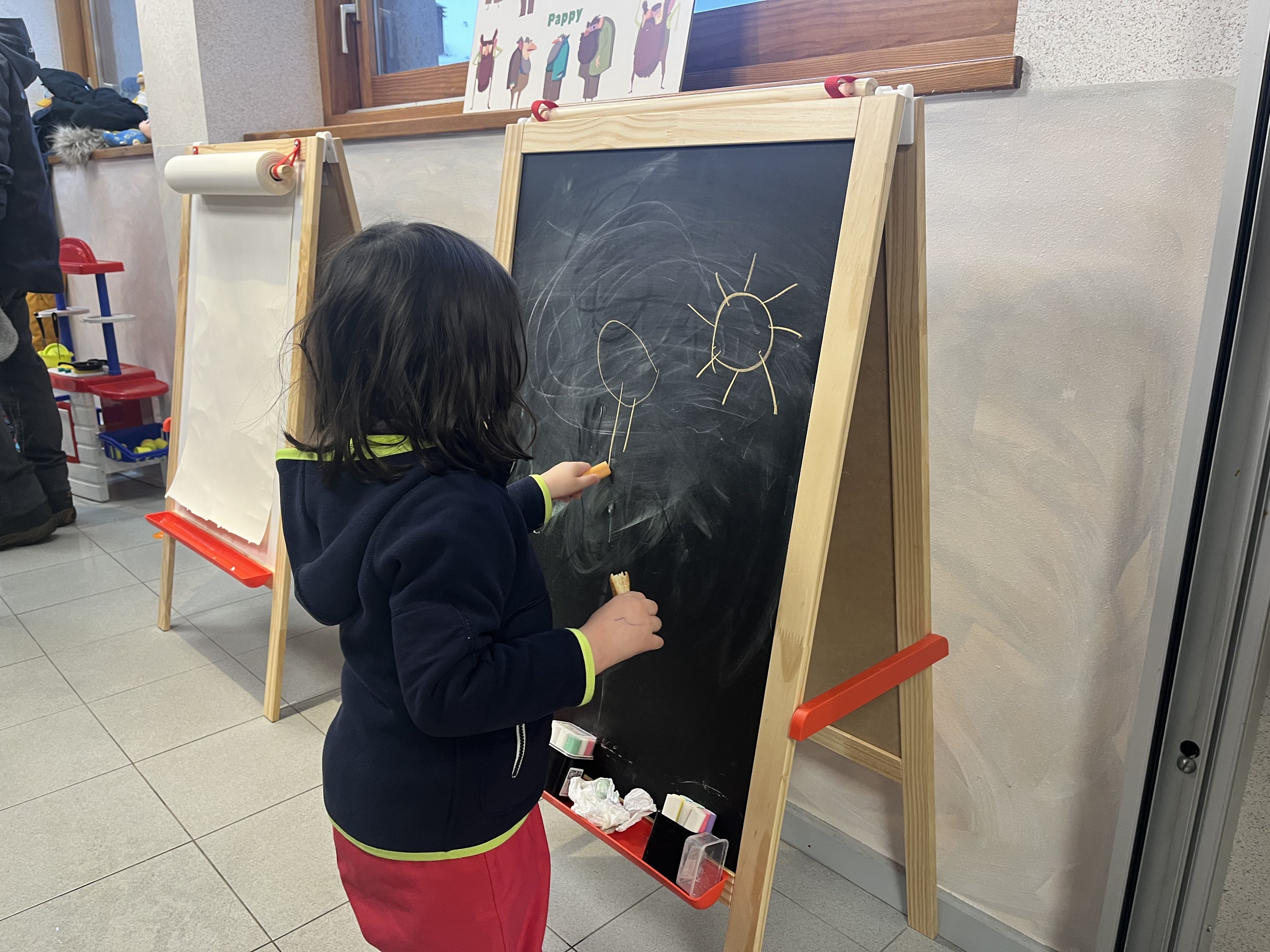 Una nena dibuixant a una de les pissarres. 