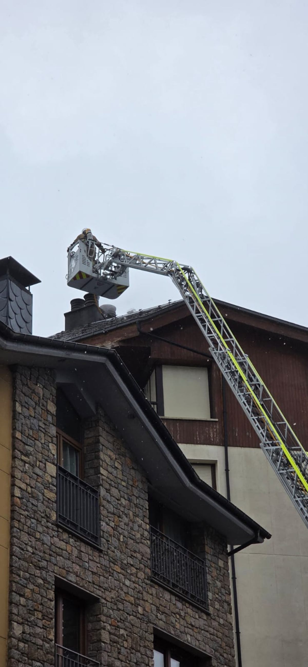 Un dels operaris dels bombers, examinant la xemeneia de l'edifici.