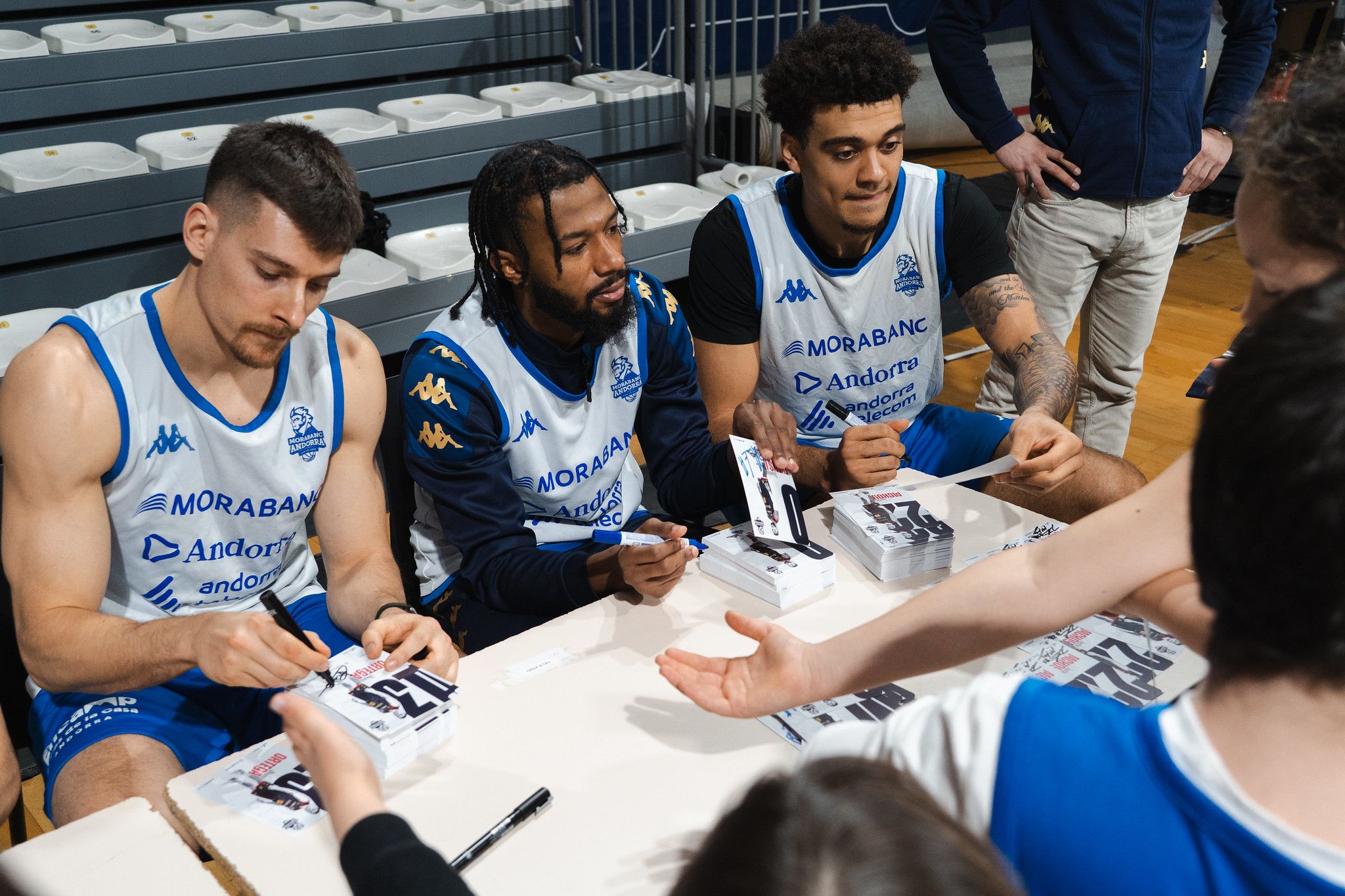 Tres dels jugadors del MoraBanc signant fotografies. 