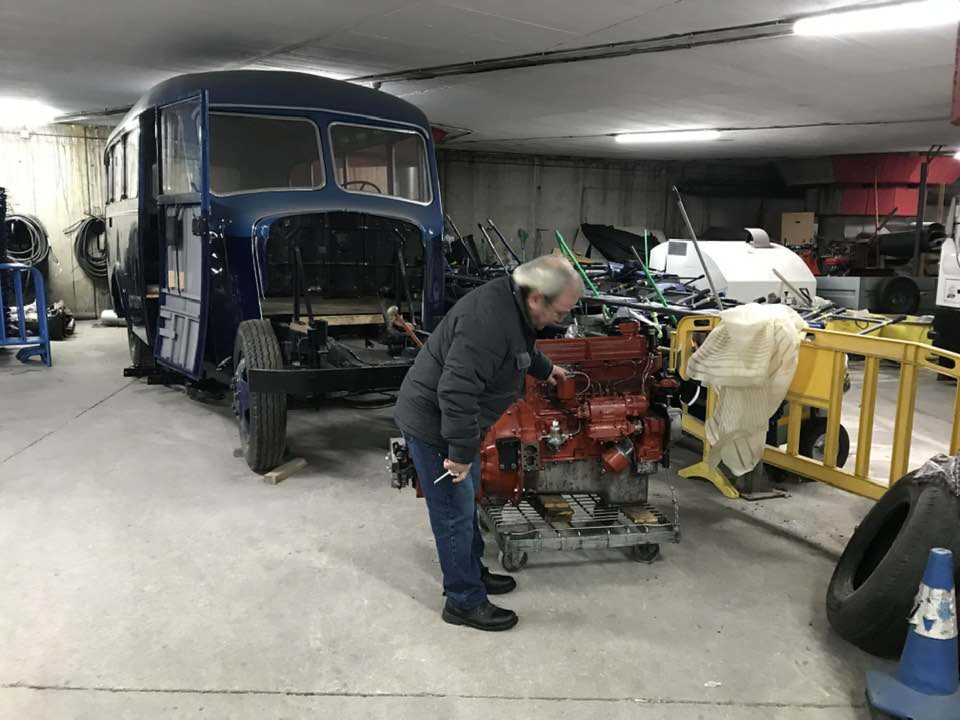 El mecànic que treballa en el motor del Fargo amb el vell Dodge al darrere.