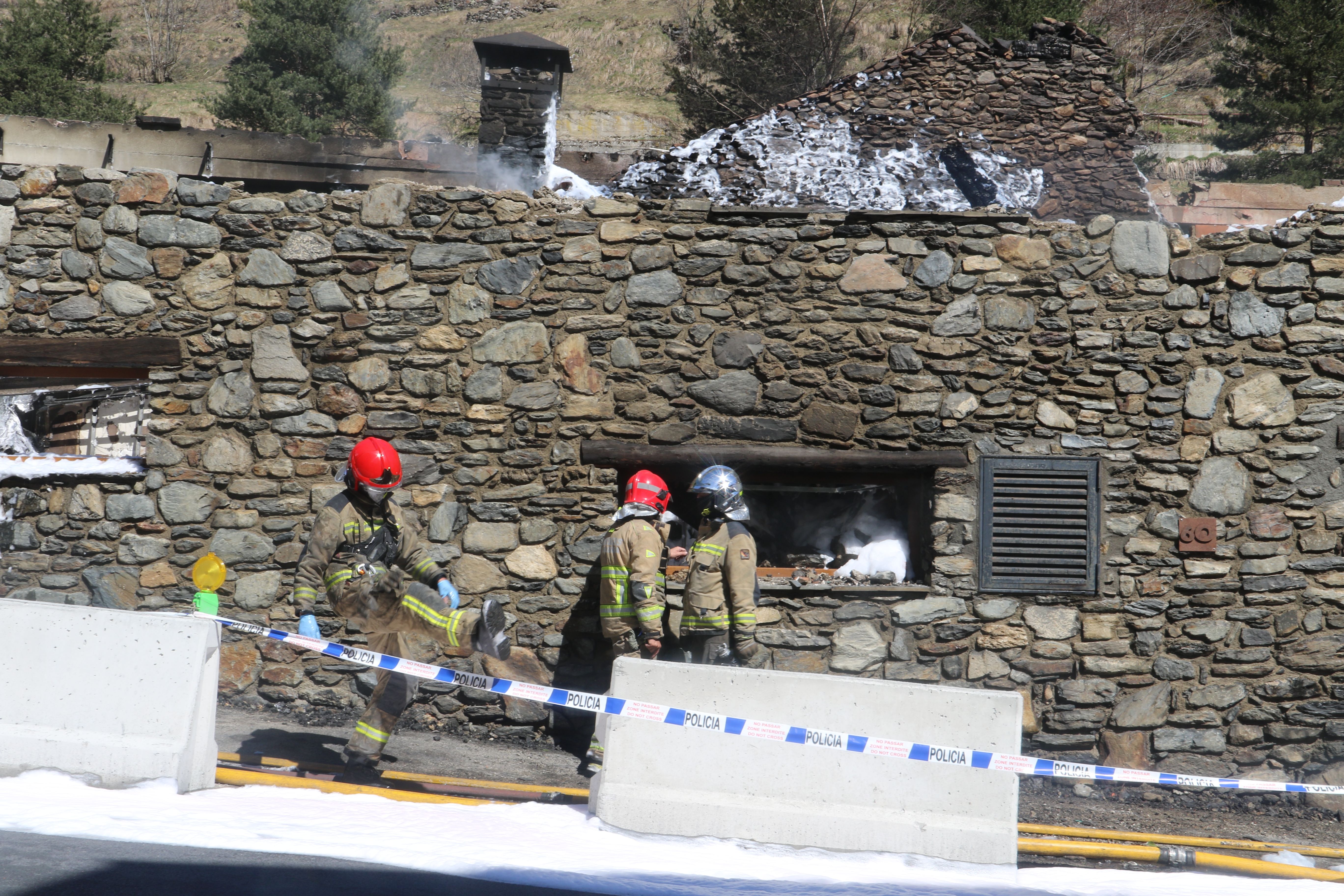 Bombers mirant de refredar l'edifici derruït. 