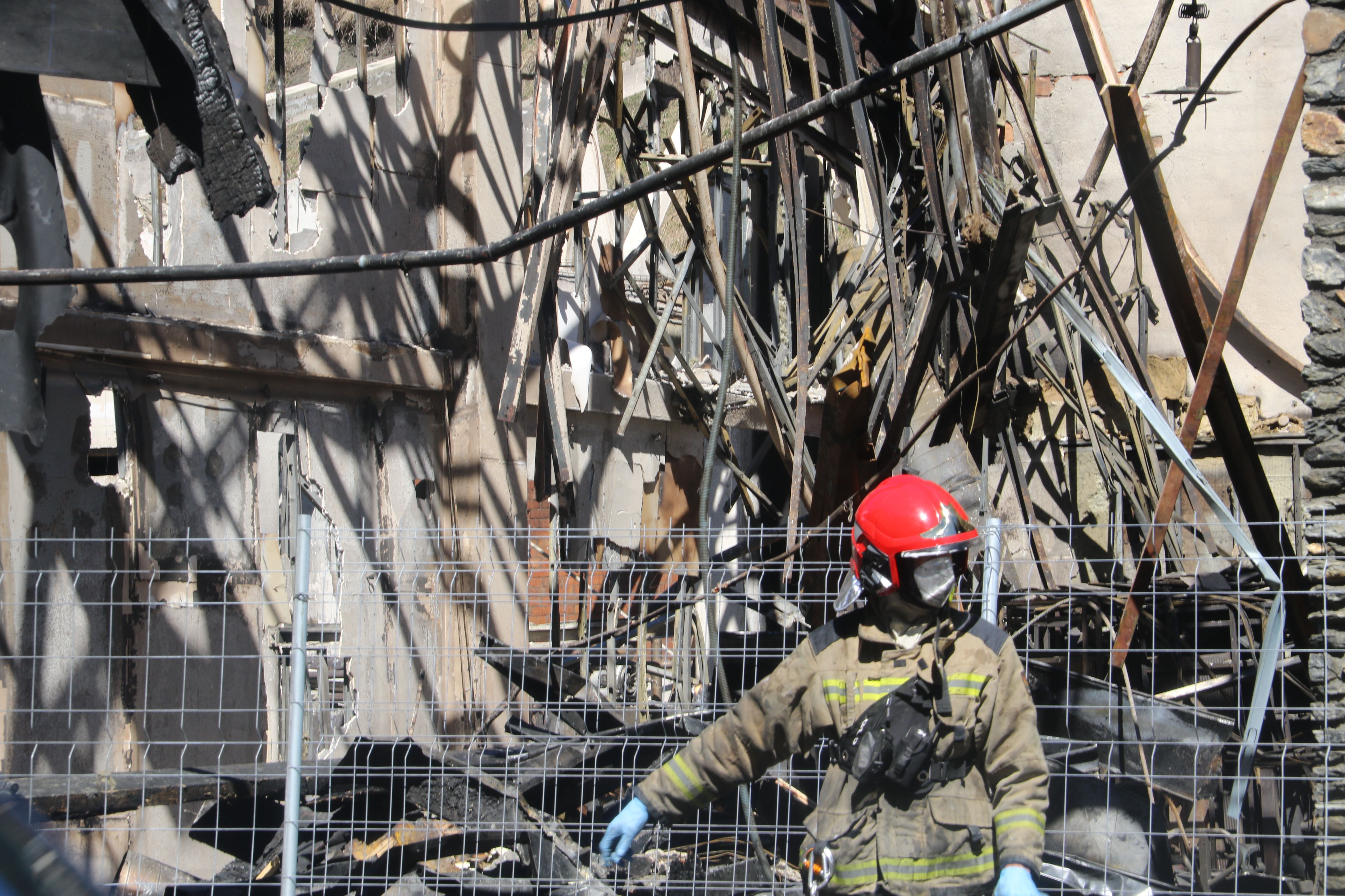 Un bomber passa davant de l'estructura derruïda de la fàbrica.