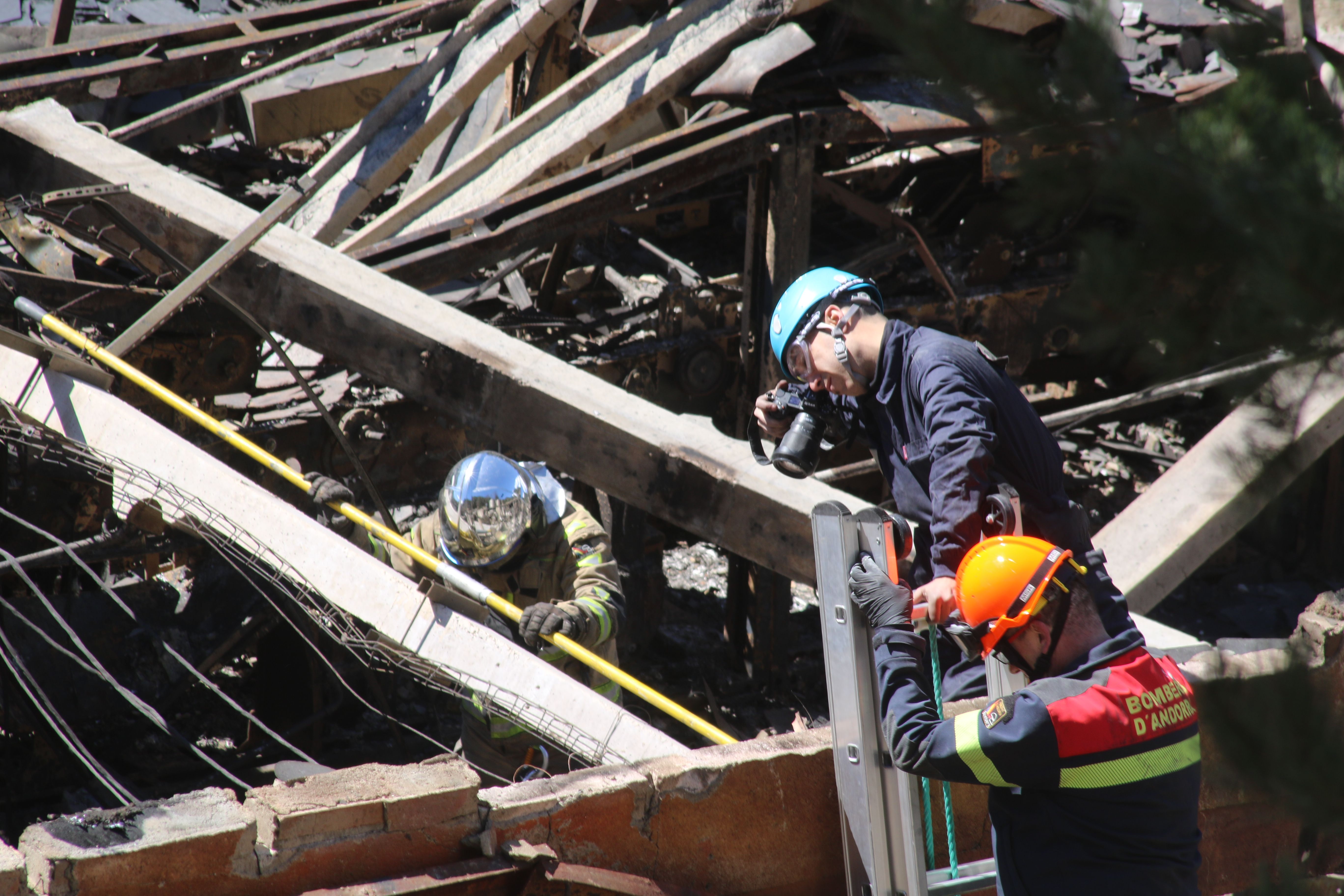 El cap de la policia científica pren imatges de les zones d'interès per a la investigació amb el suport d'un oficial dels bombers.