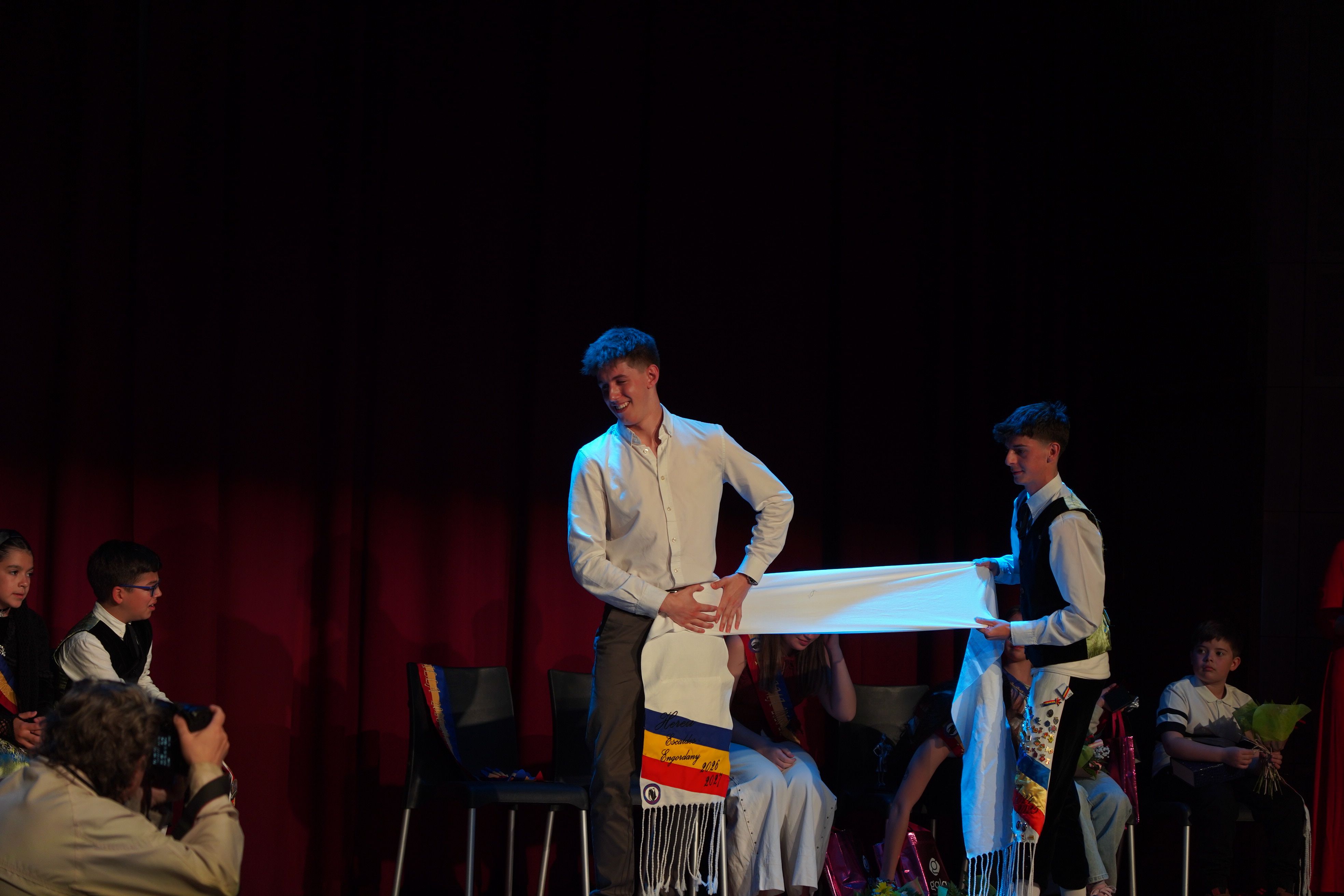 L'hereu sortint, Adrià Llobet, ajudant a posar la faixa a l'hereu entrant, Biel Molina.