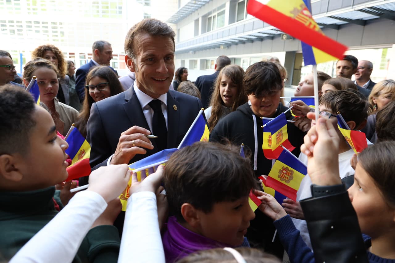 Macron signant una bandereta.