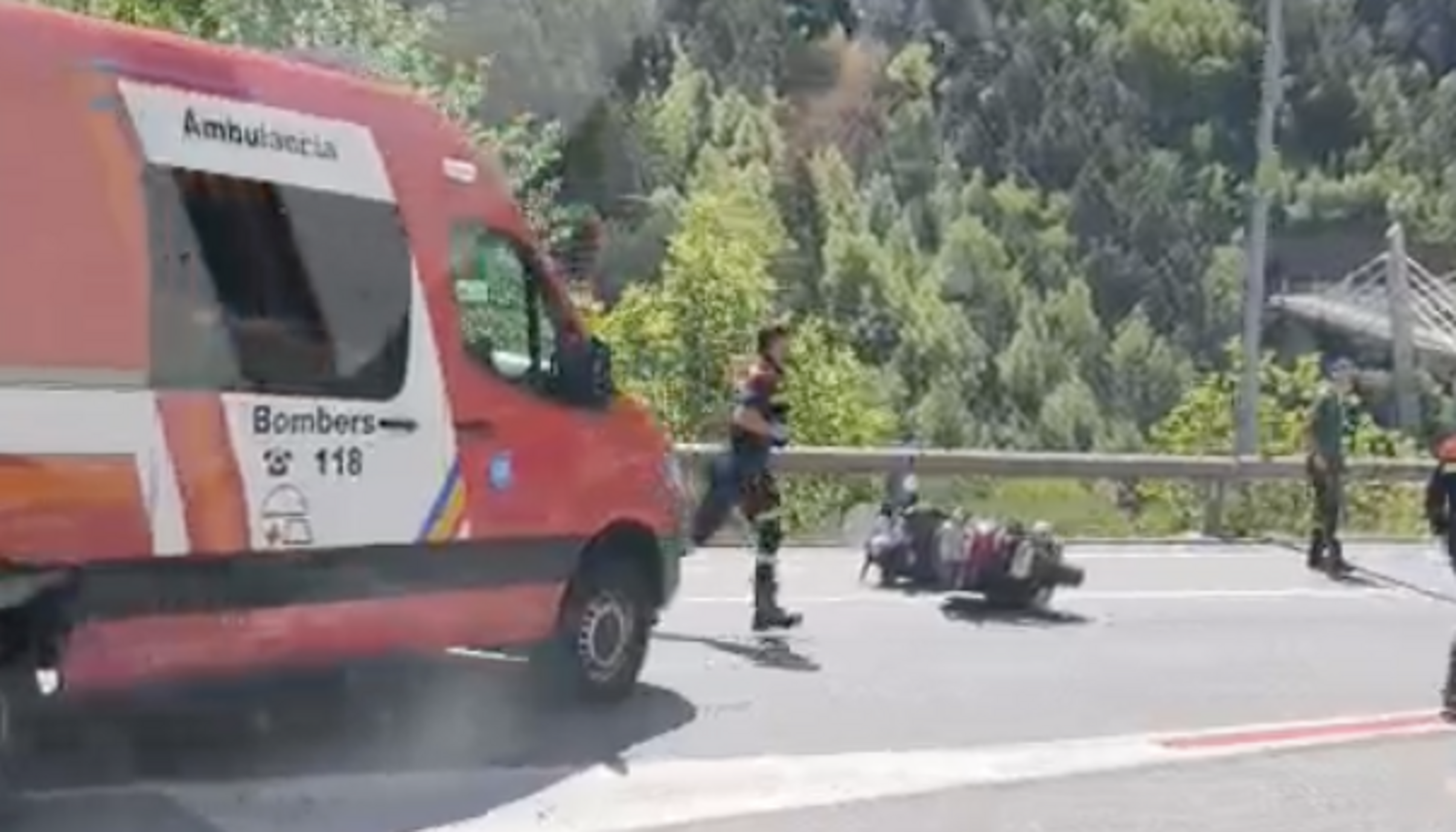 Un bomber acudeix a auxiliar l'accidentat tot passant per davant de la moto.