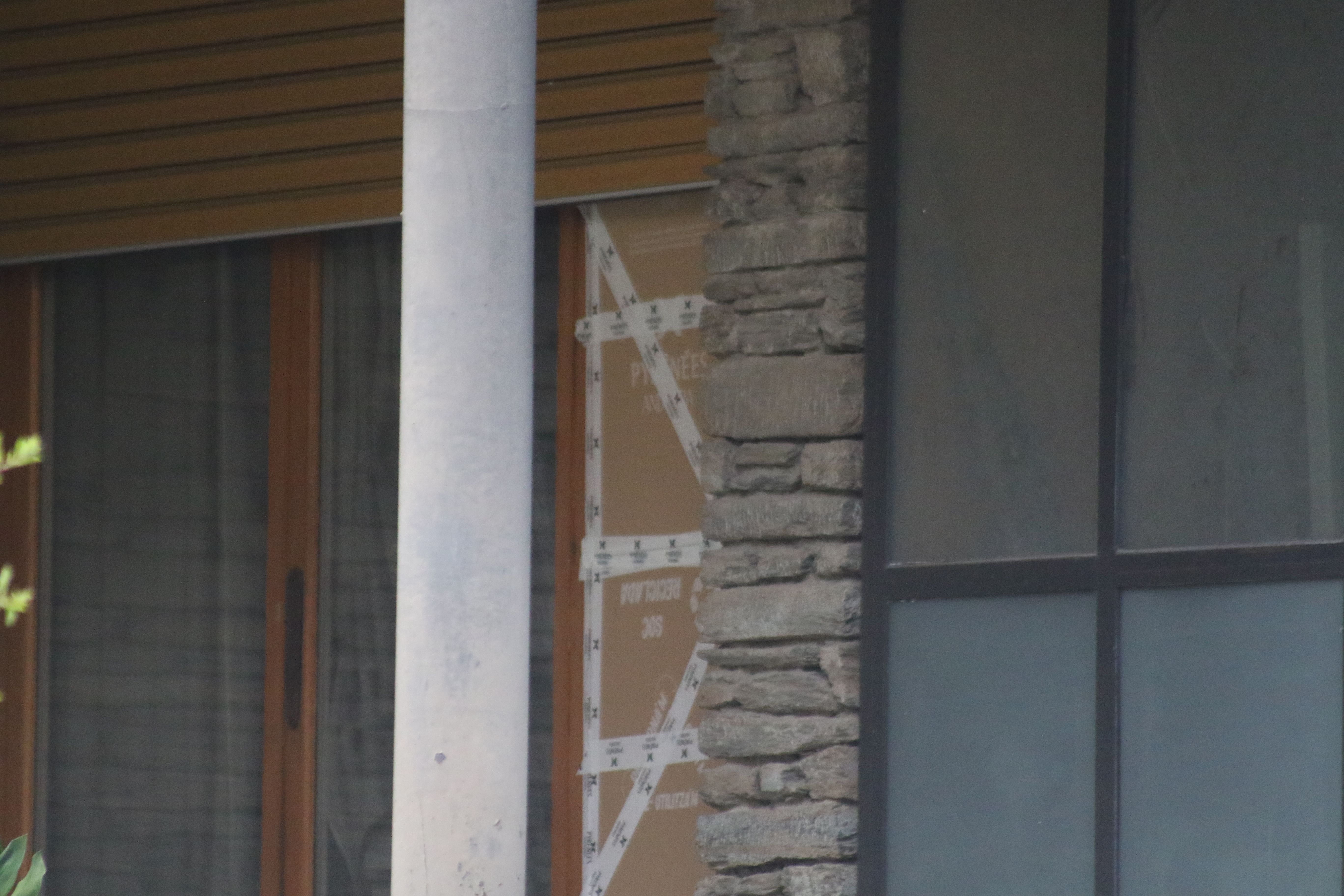 Una imatge de l'accés del xalet on van ser enxampats els dos homes, amb l'espai del vidre trencat cobert per cartrons. Una imatge de l'accés del xalet on van ser enxampats els dos homes, amb l'espai del vidre trencat cobert per cartrons.