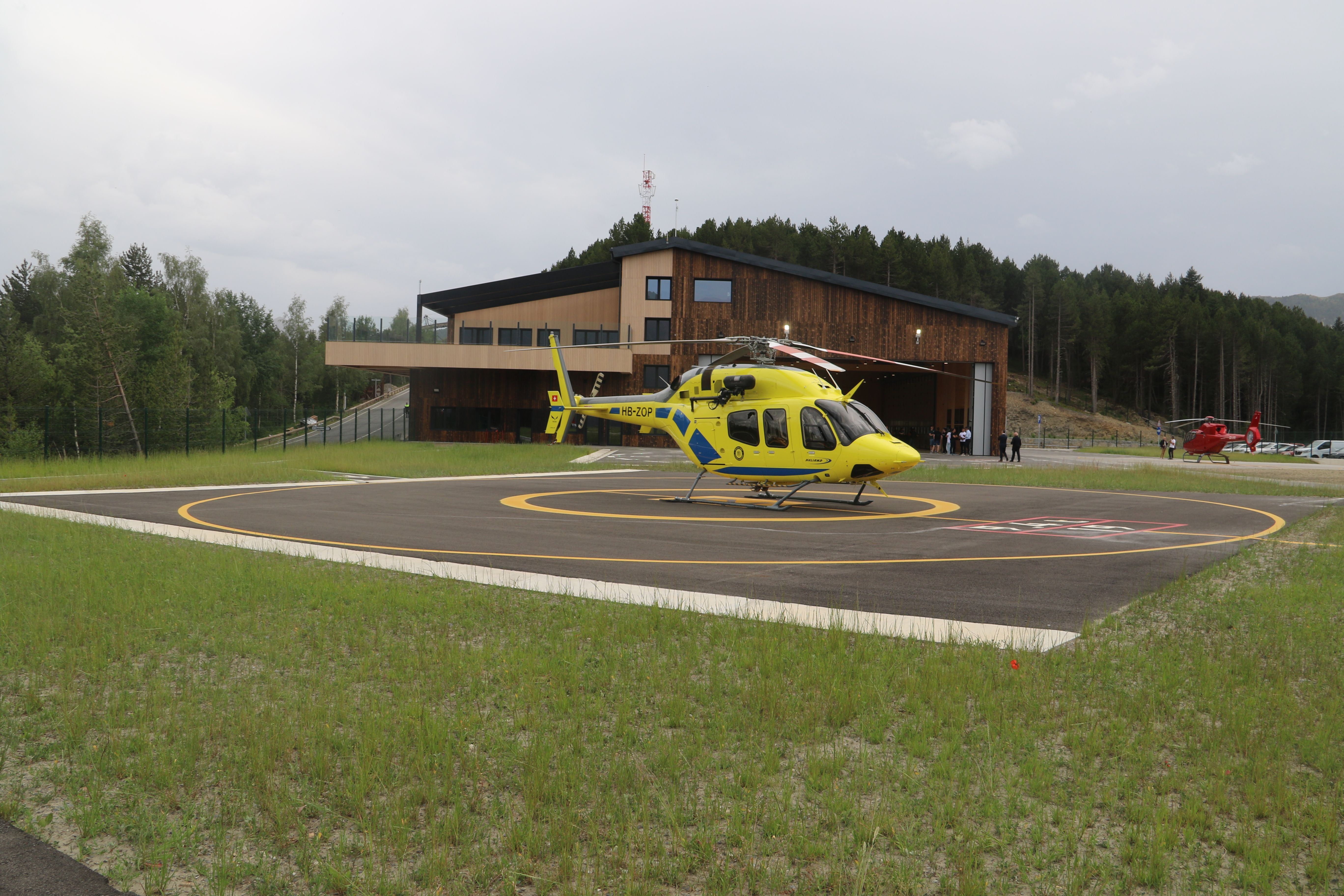 Un helicòpter amb l'hangar de fons.