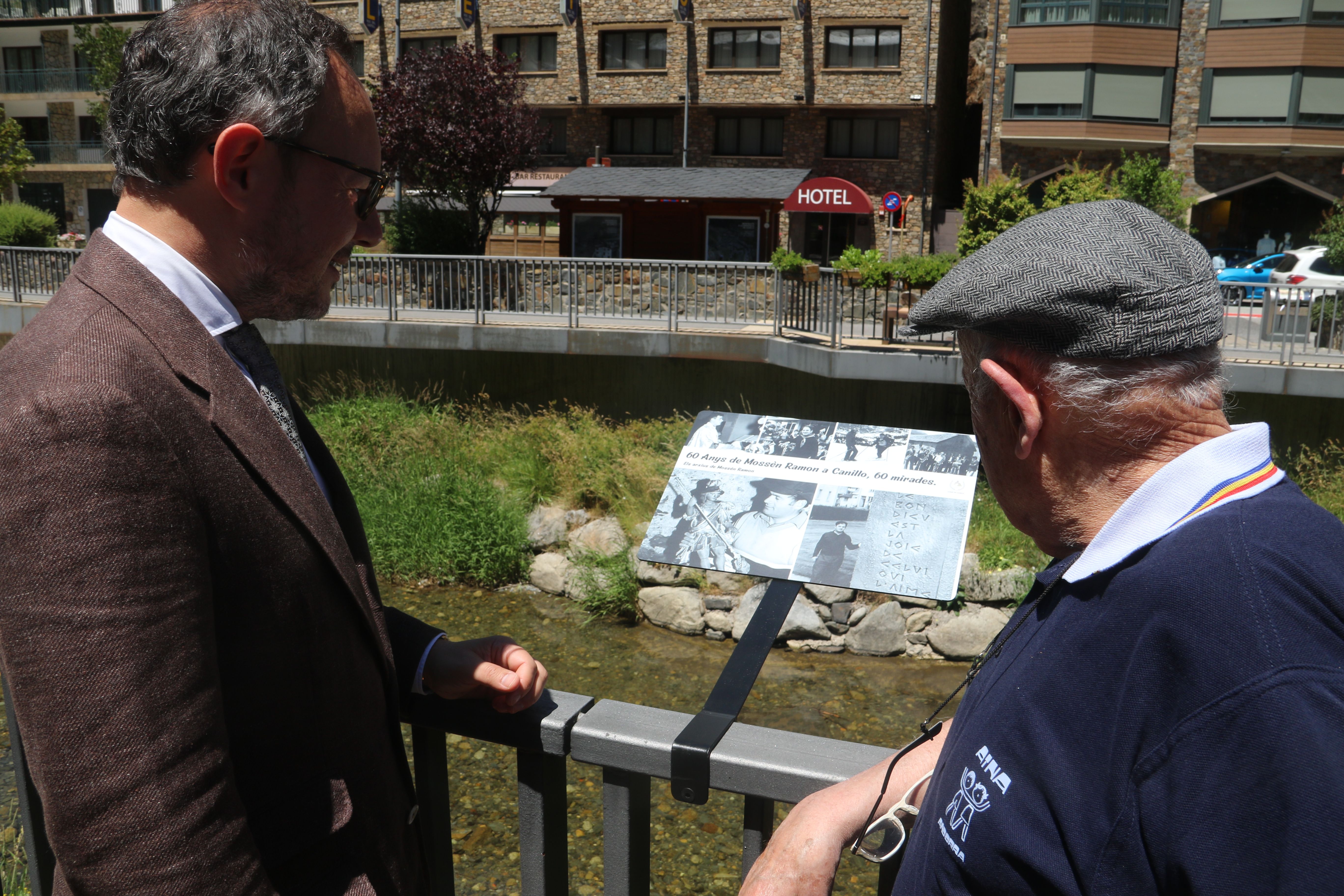 Xavier Espot i mossèn Ramon observant la primera de les fotos de l'exposició a l'aire lliure.