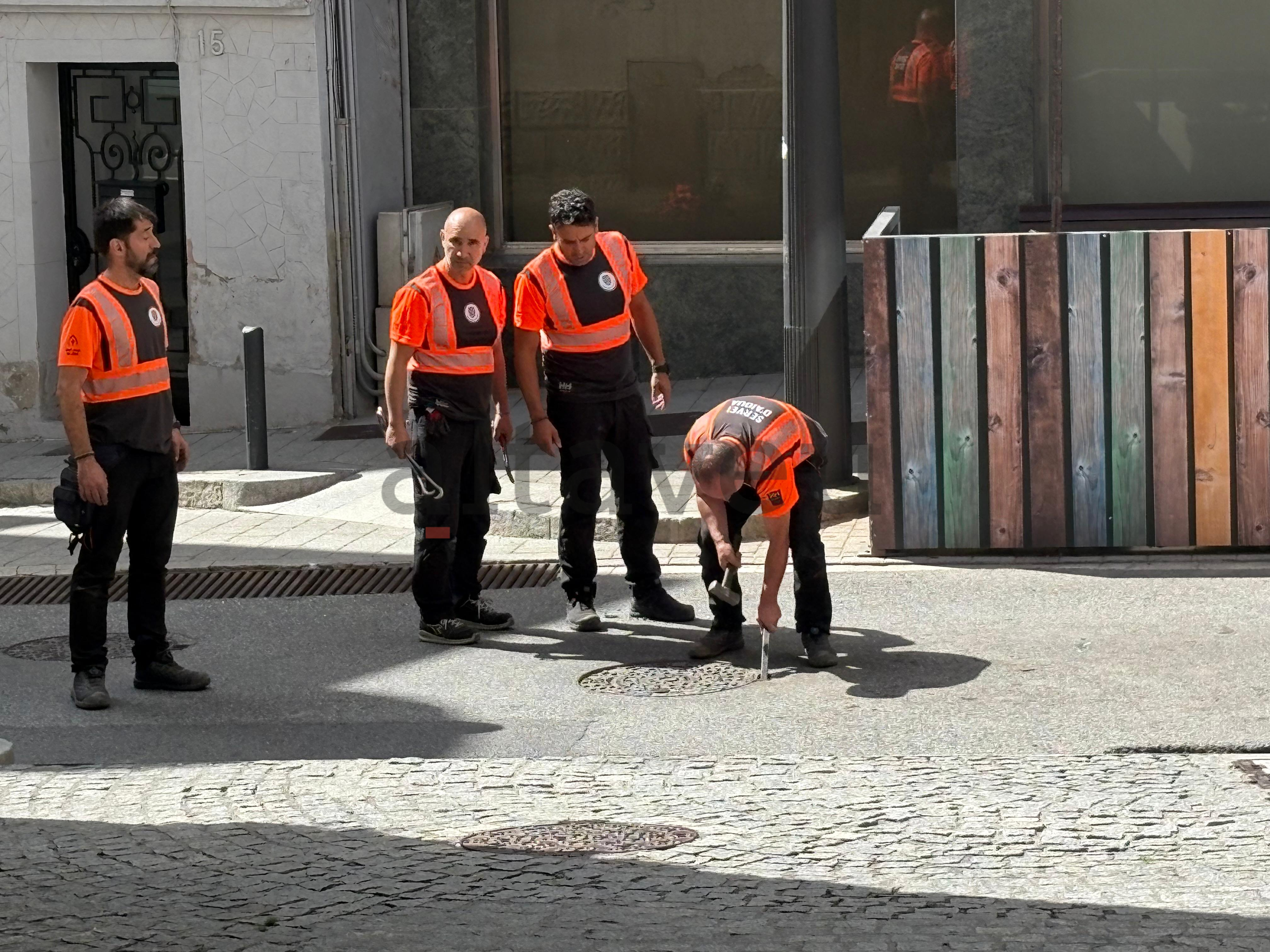 Operaris comunals revisant els accessos al clavegueram.