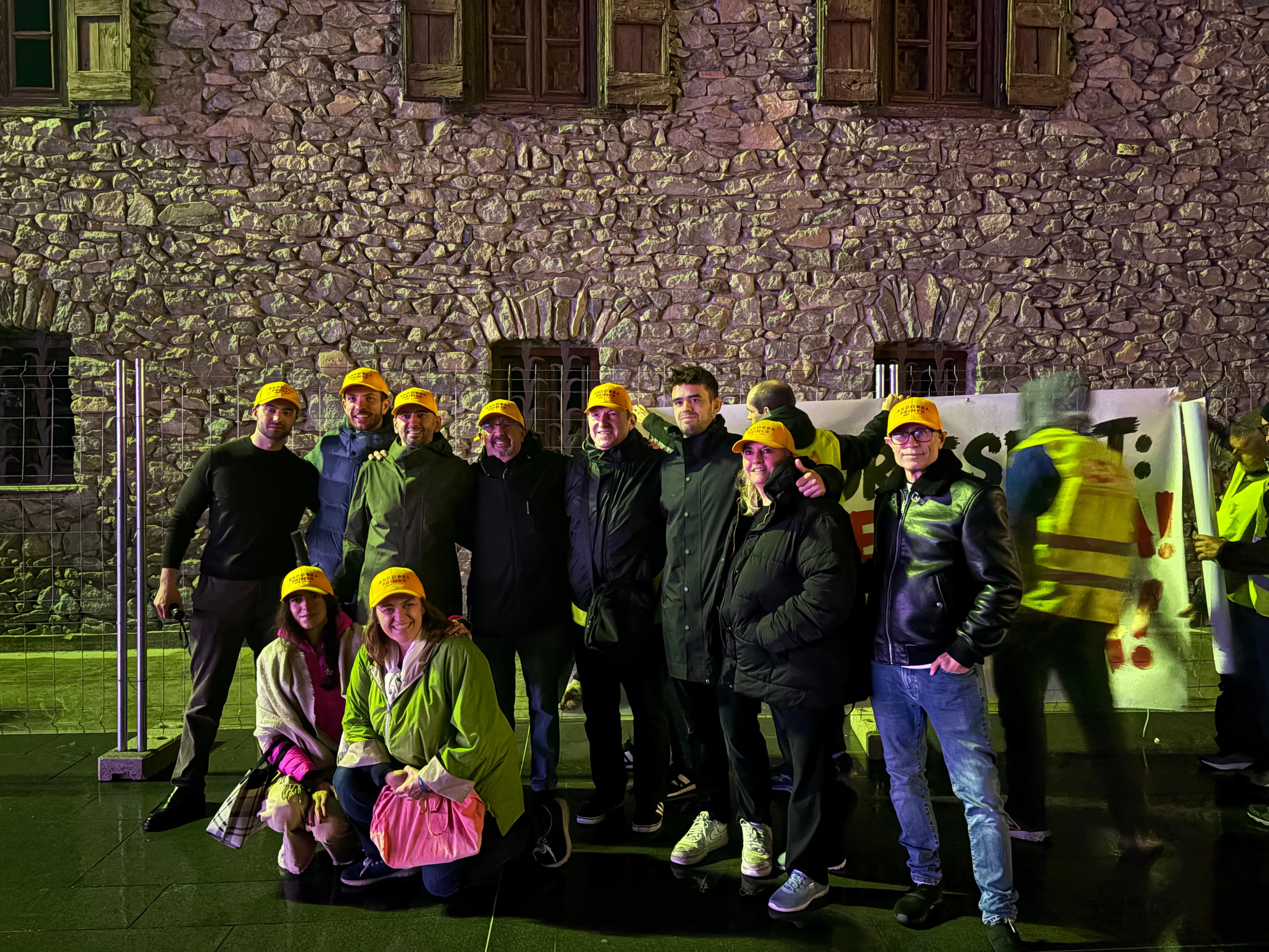 Diversos assistents amb gorres d’Andorra Primer, davant de les pancartes que reclamen la celebració del referèndum. | A.O.G.