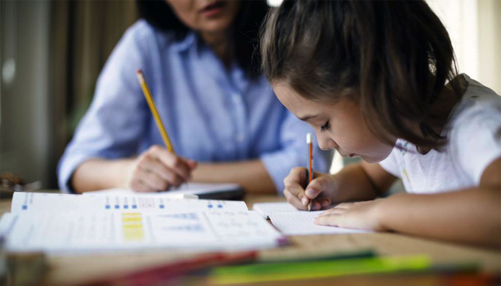 Una mare ajudant la seva filla a fer els deures.