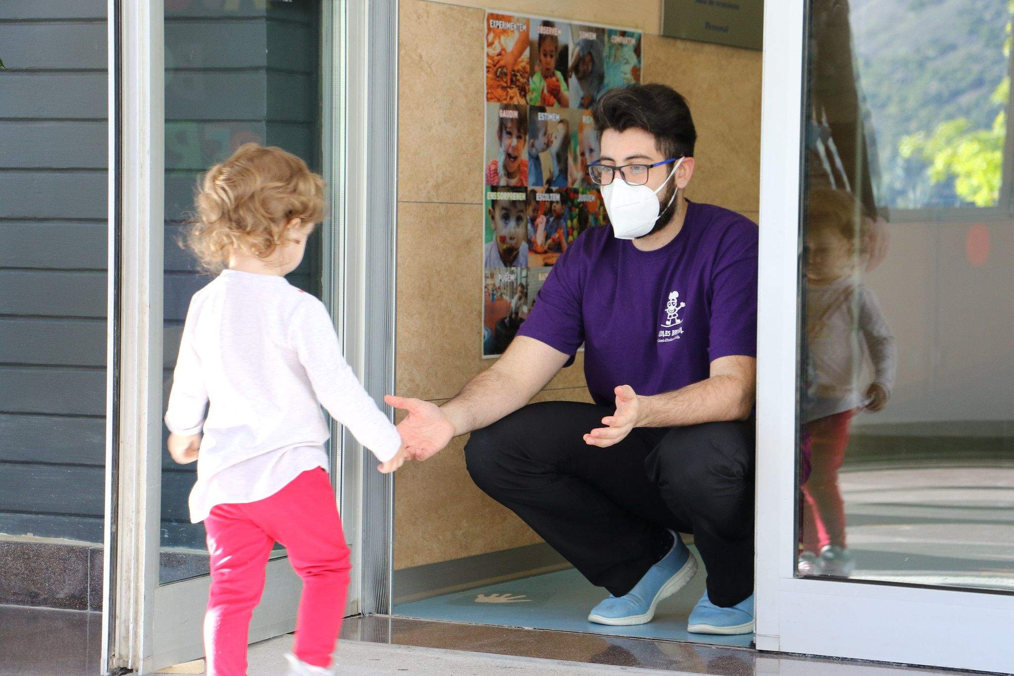 Un dels monitors rep un dels infants que han anat el dia de la reobertura.