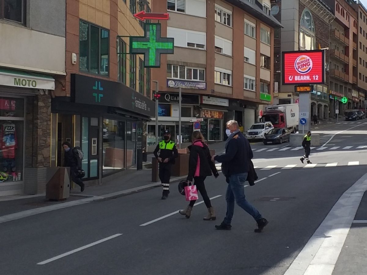 Dos visitants canvien de vorera seguint les indicacions d'un agent de circulació.