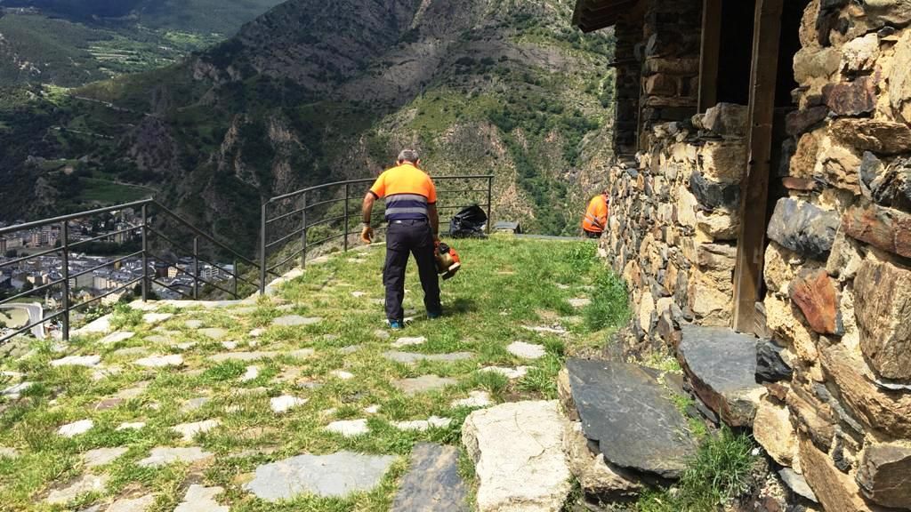 Treballadors del comú de Sant Julià netejant l'entorn de Sant Serni de Nagol.