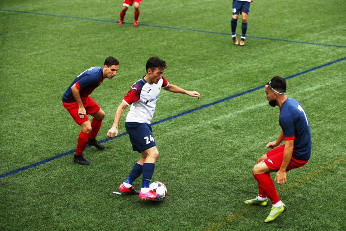 Un jugador de Vall Banc intenta fer jugada entre dos rivals del Sant Julià.