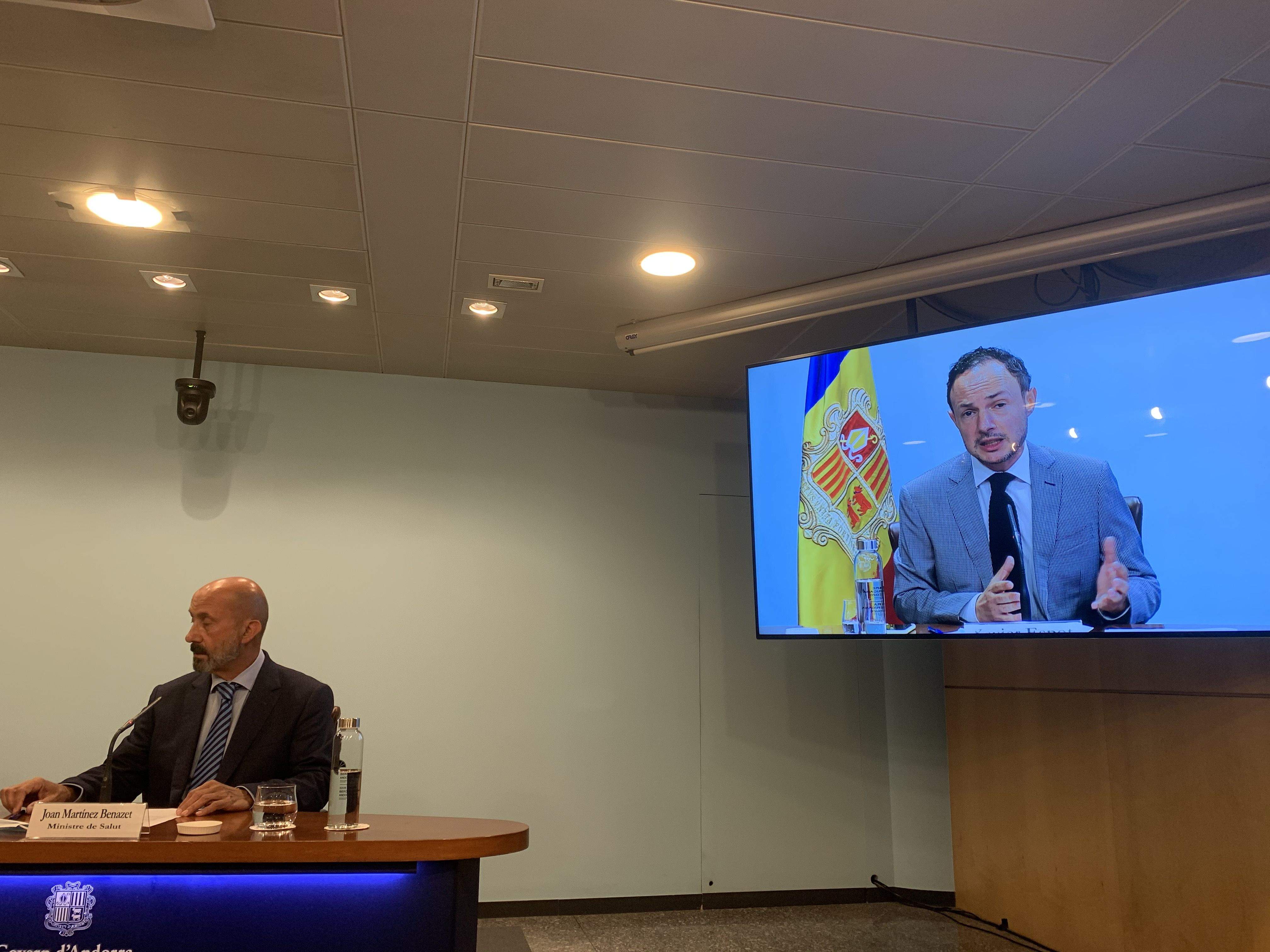El ministre de Salut, Joan Martínez Benazet, escolta la intervenció del cap de Govern, Xavier Espot, projectada a la pantalla.
