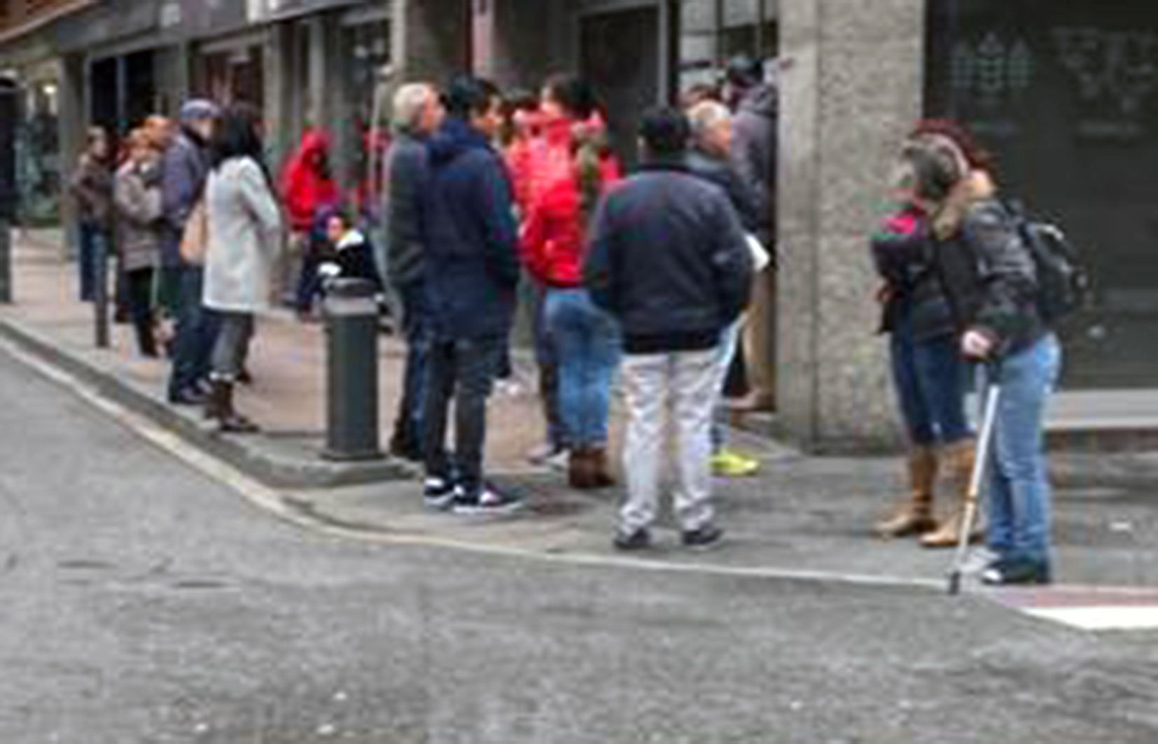 Ciutadans esperant al peu de la porta d'un comerç que va ser clausurat unes hores per no disposar de guants.