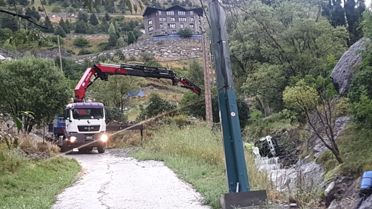 Una grua treballa per retirar el vehicle d'on ha caigut.
