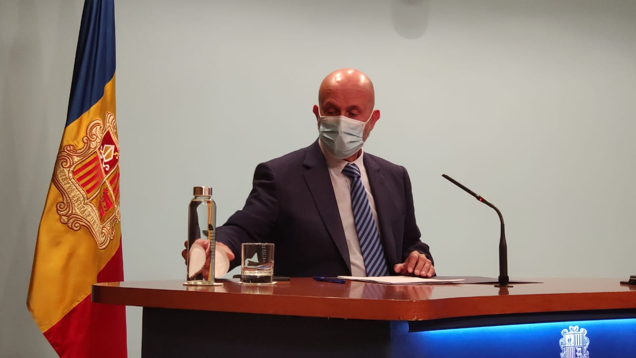 El ministre de Salut agafant una ampolla d'aigua durant la roda de premsa.