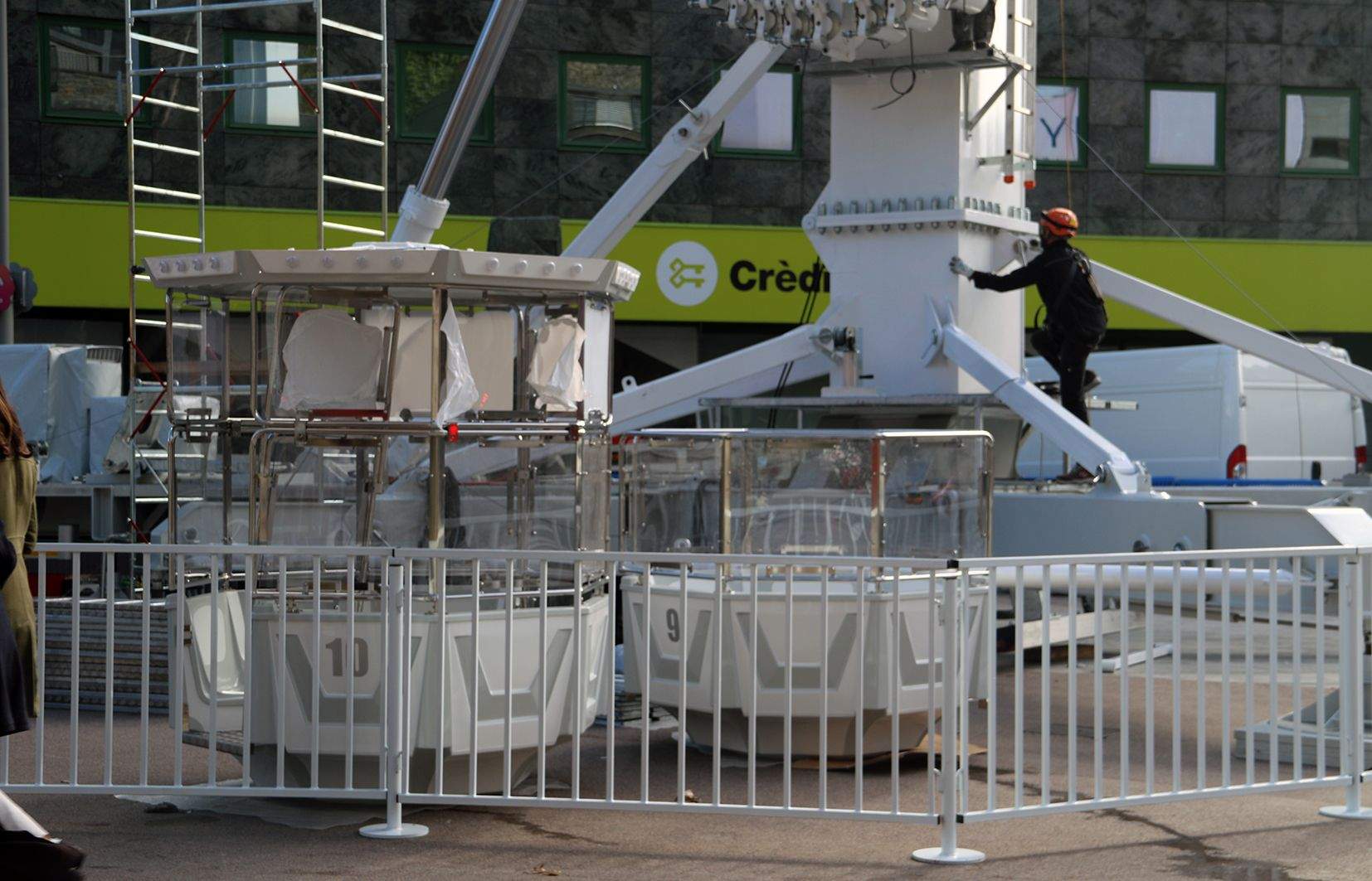 Un operari s'enfila a la nòria, amb dues de les dotze cabines en primer terme.