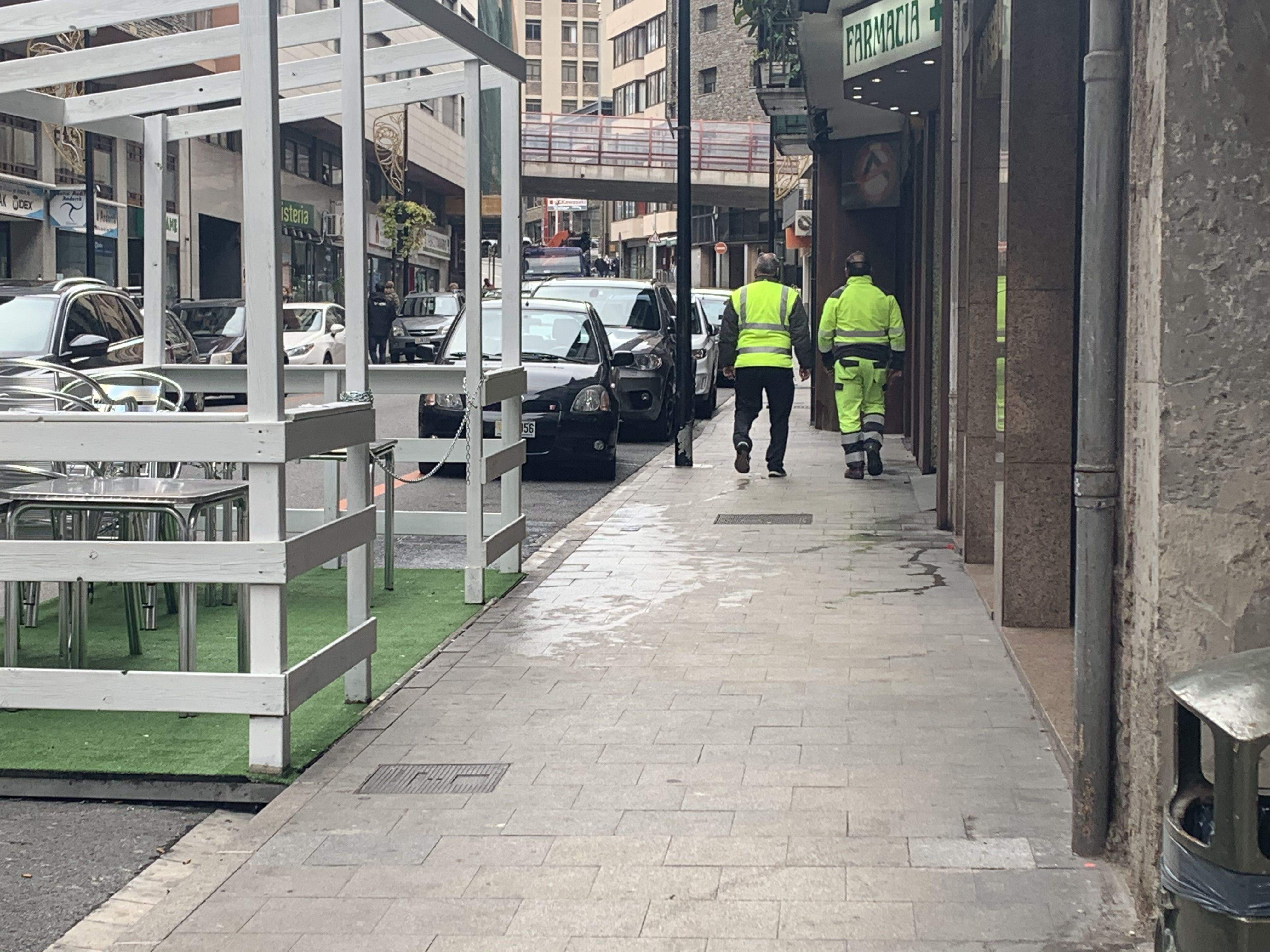 Dos operaris passen pel punt on ha estat localitzat l'home poc després que es netegés la voravia.