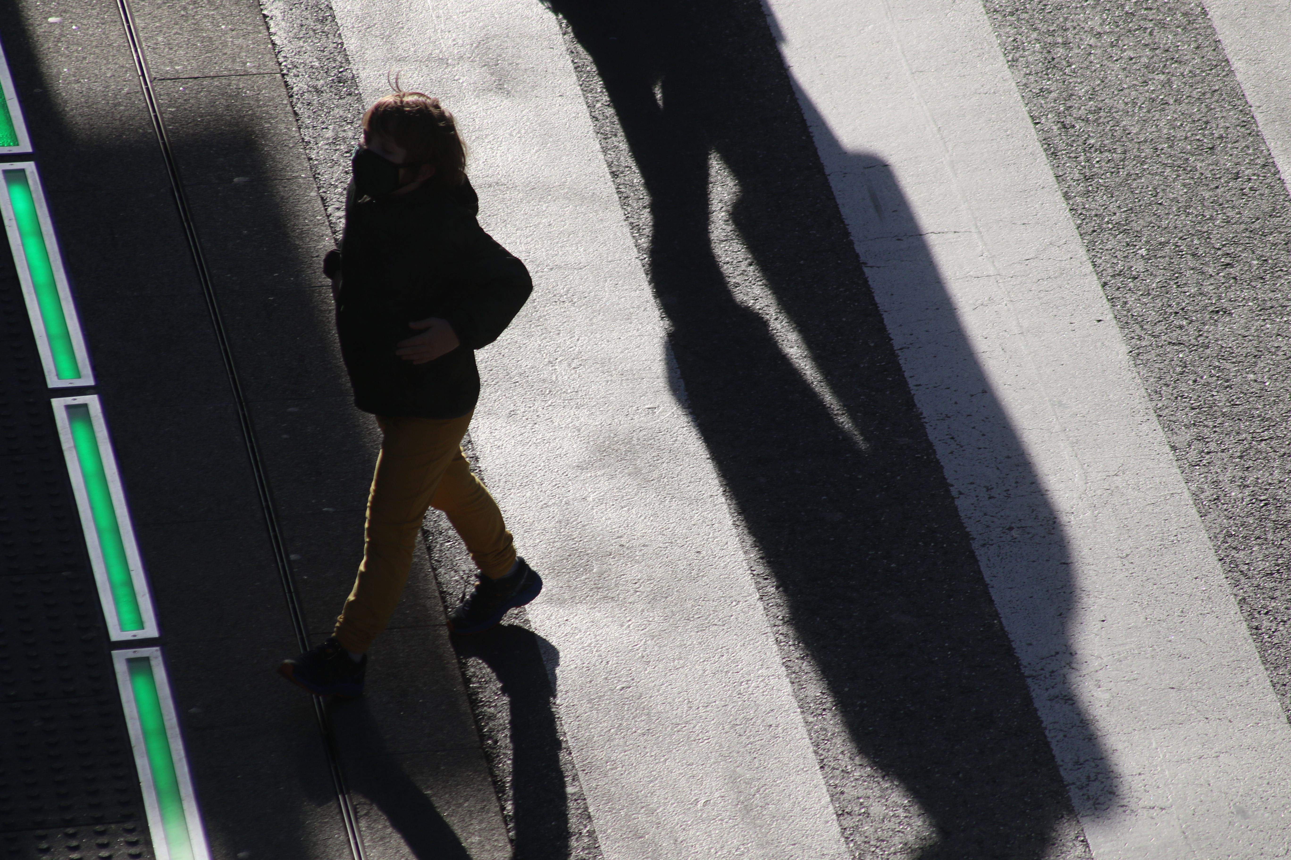 Un infant creuant un pas de vianants amb la mascareta posada.