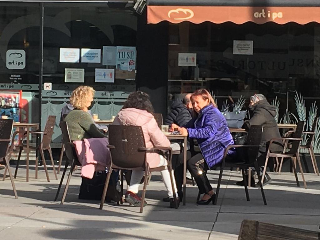 Un grup de tres persones a una terrassa de la plaça Germandat, a Sant Julià.