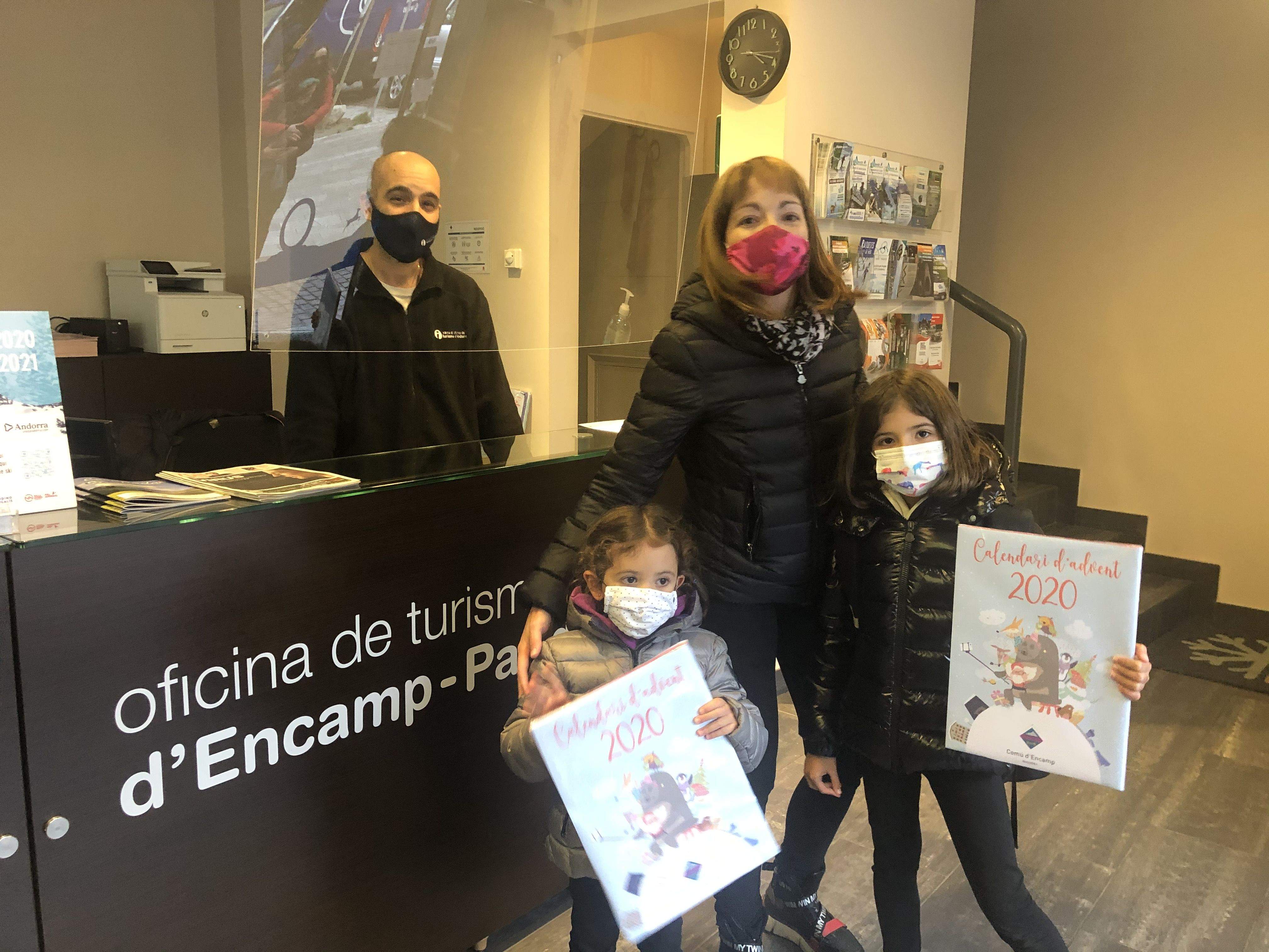Dues nenes acompanyades de la seva mare recullen el calendari d’Advent a l’oficina de turisme.