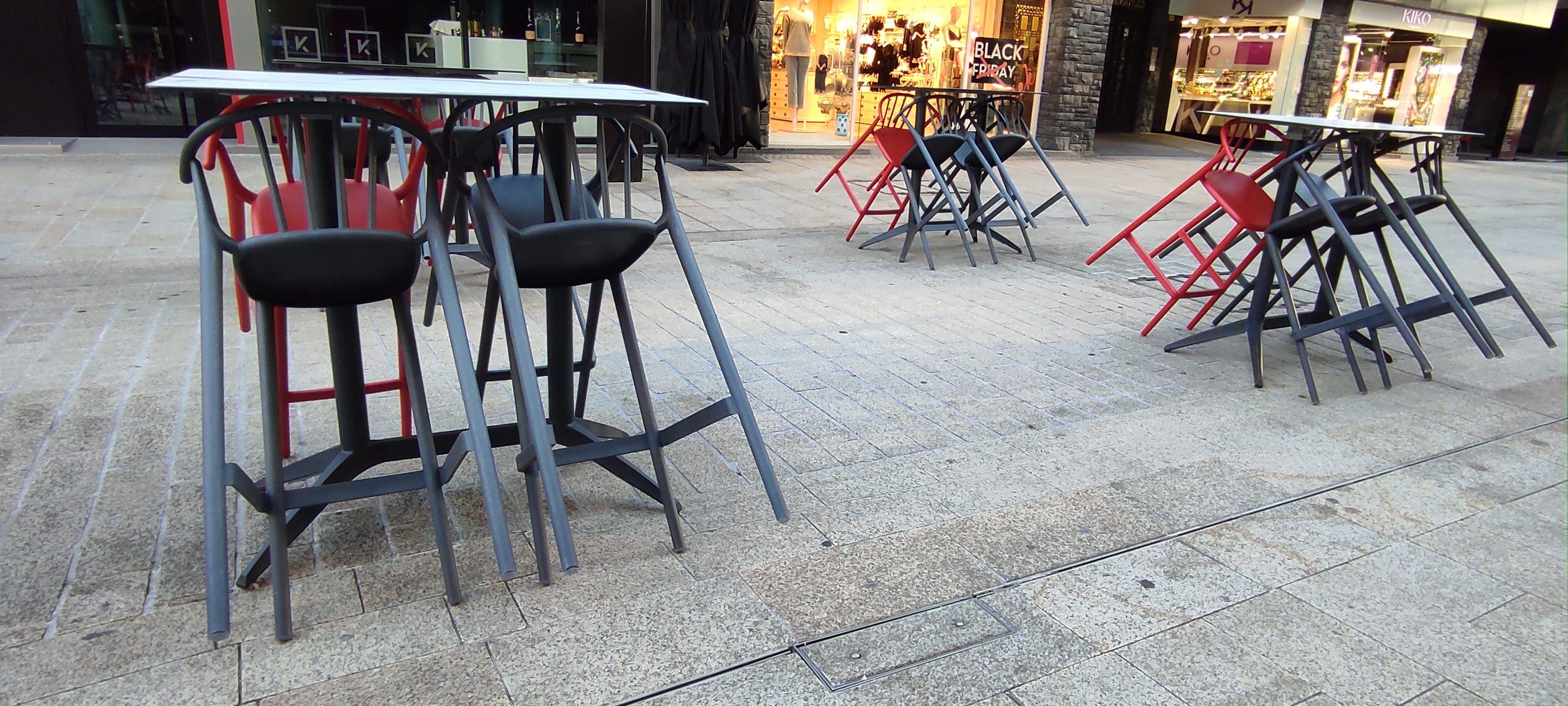 Taules i cadires sense ocupar en una terrassa.