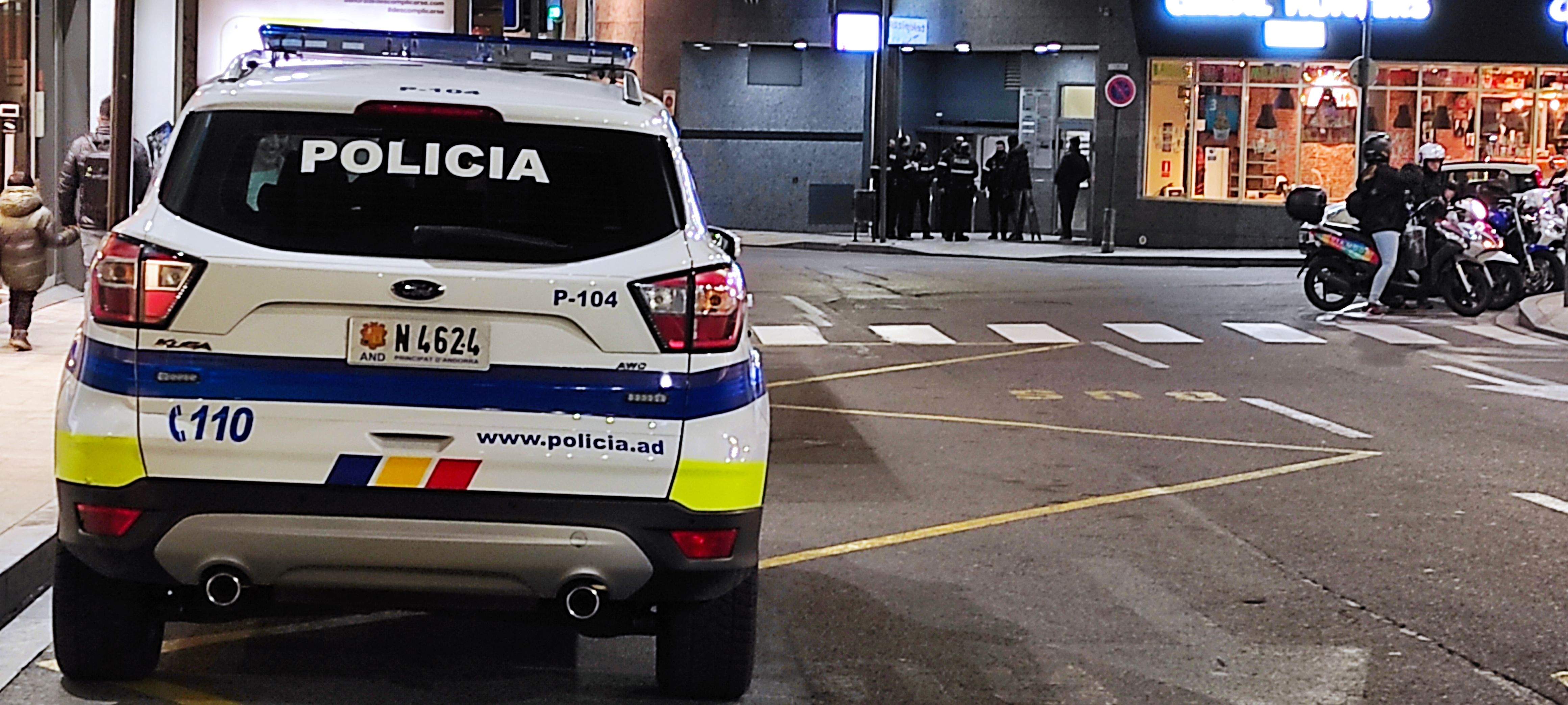 Un dels cotxes patrulla en primer terme amb els agents, al fons, encerclant l'implicat.