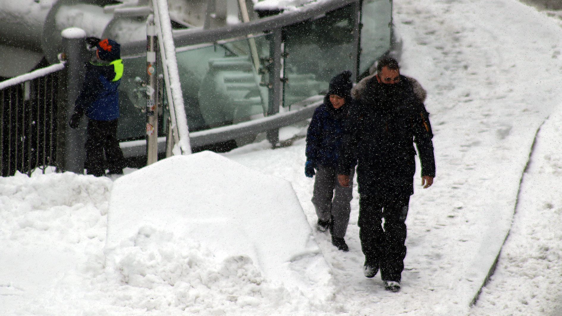 Un home i els seus fills enmig de la nevada a Andorra la Vella.