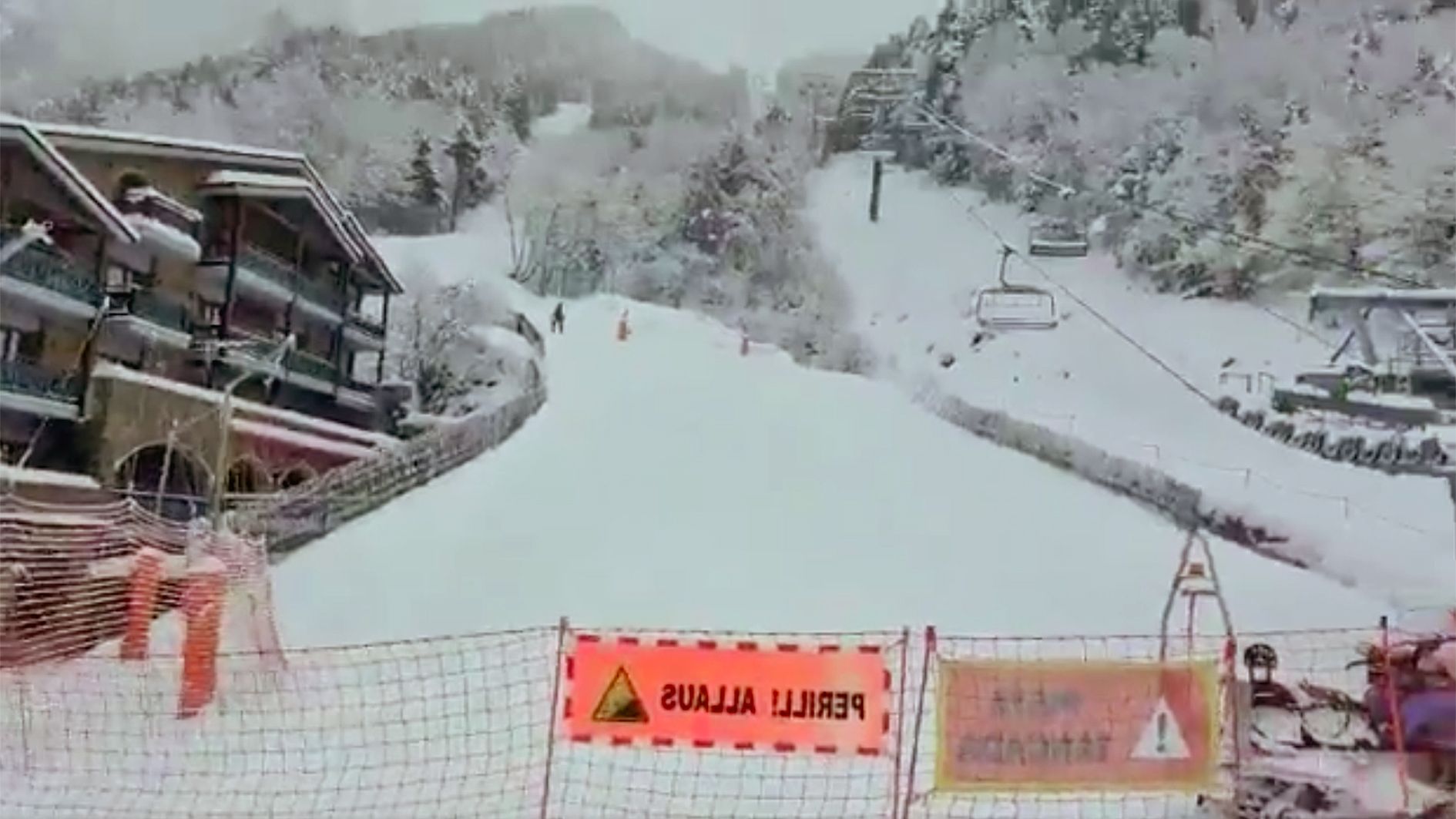 Les xarxes i els rètols advertint del perill d'allaus i, al fons, alguns esquiadors.