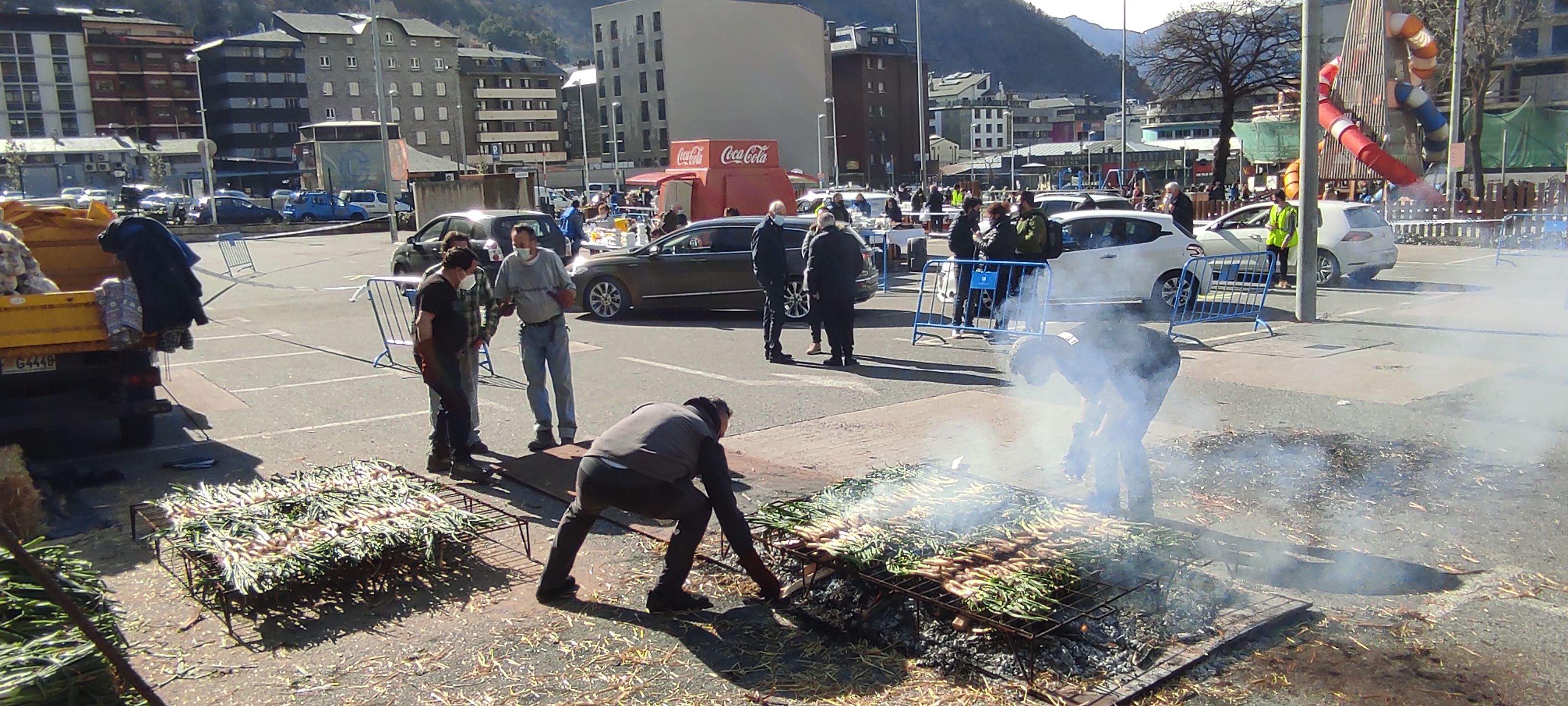 Els calçots coent-se, en primer terme, i els cotxes que passaven a recollir-los, al fons.