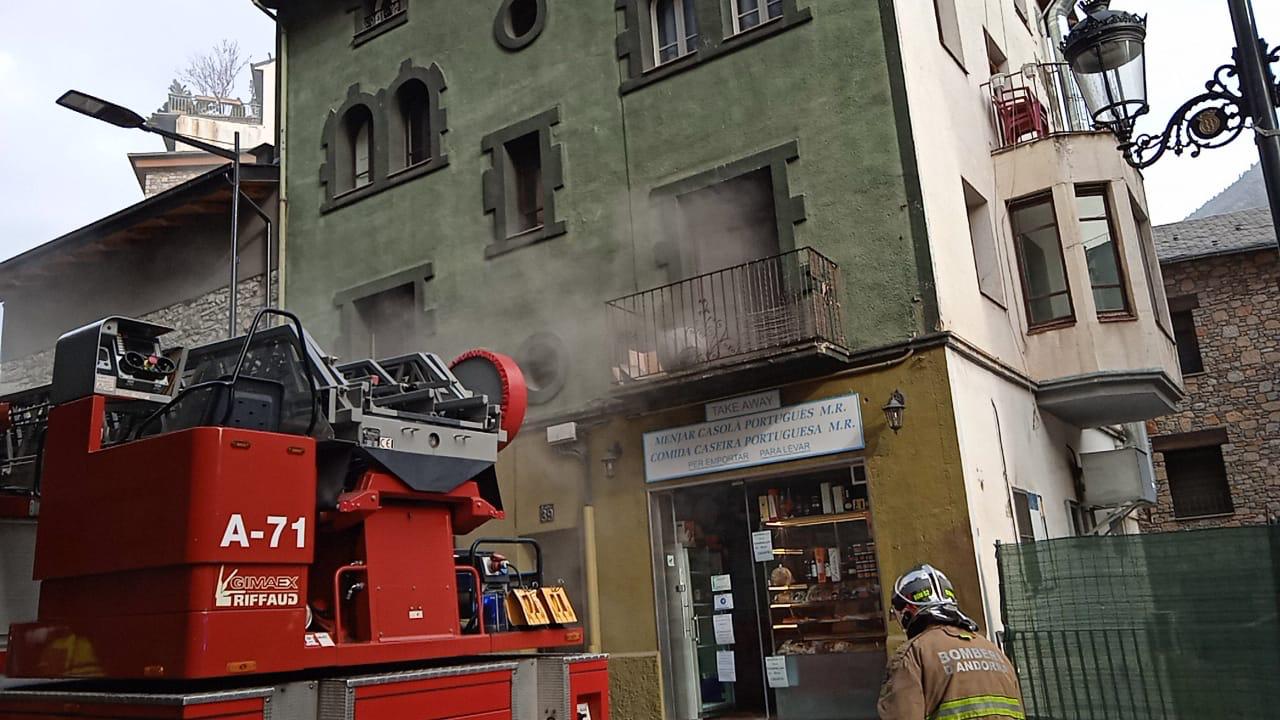 El fum sortint per la finestra del pis afectat, amb els bombers preparant la intervenció.