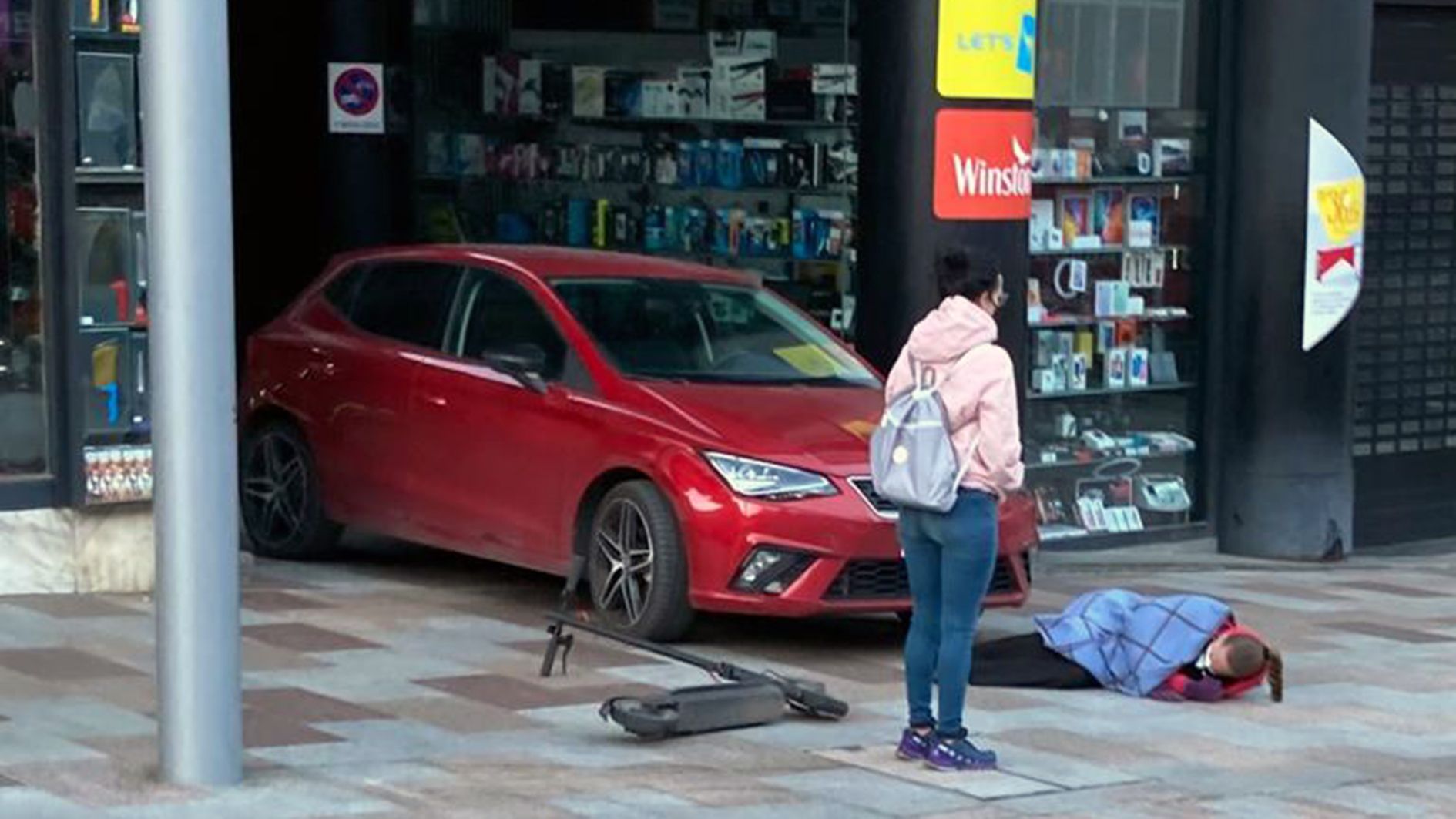 El patinet, el vehicle i la noia ferida estesa al terra.