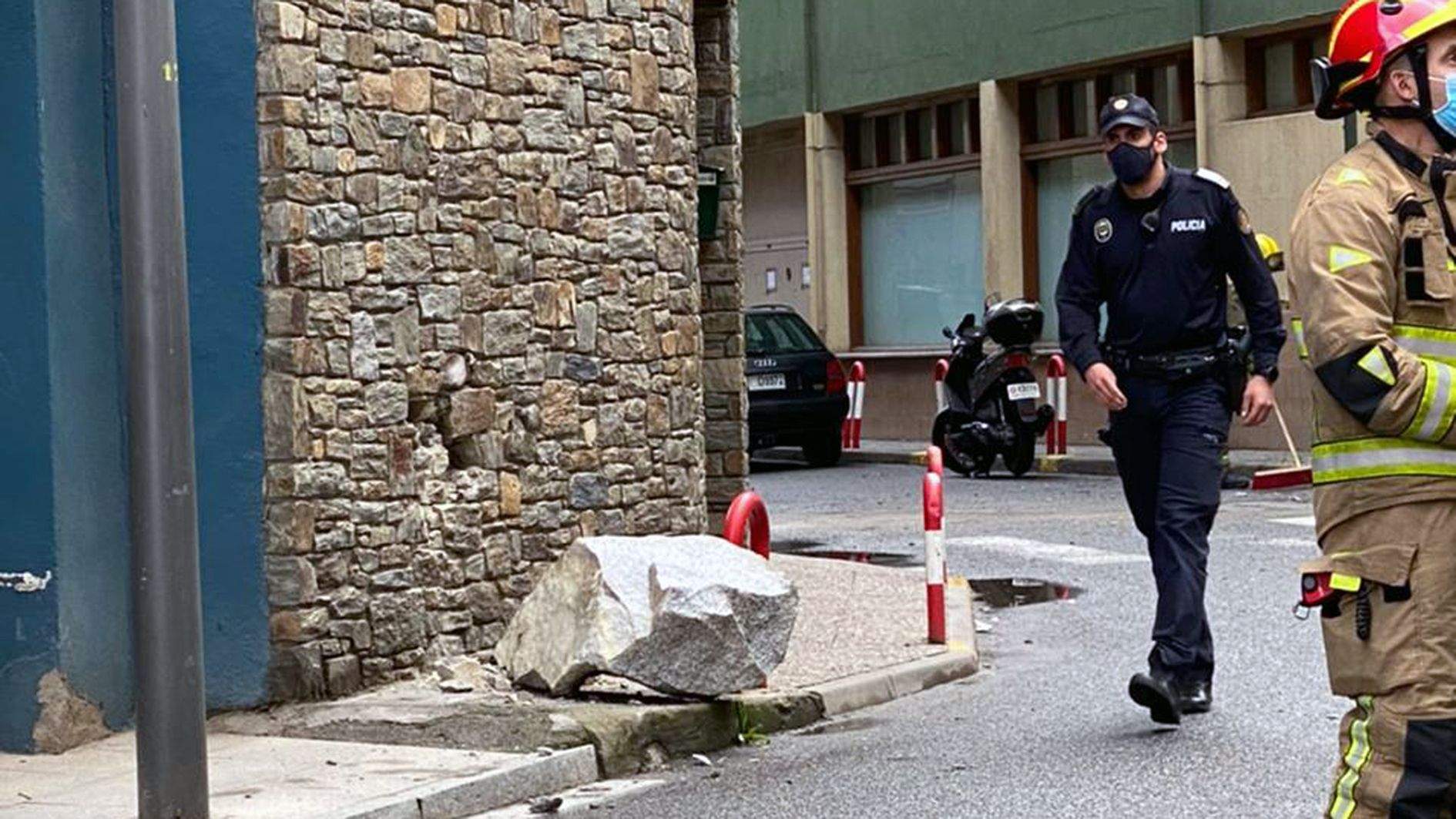Un agent de policia i un bomber al costat del roc més gran que ha aconseguit superar la barrera.