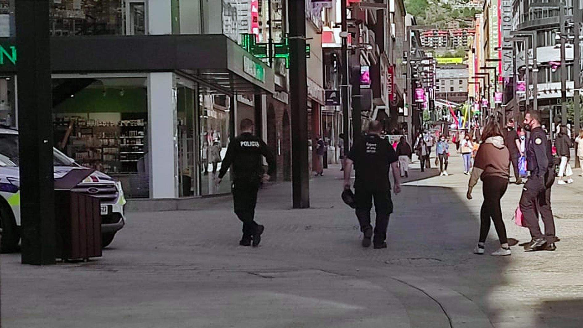 Els agents acompanyen la jove enmig de l'avinguda Meritxell cap al cotxe policial.