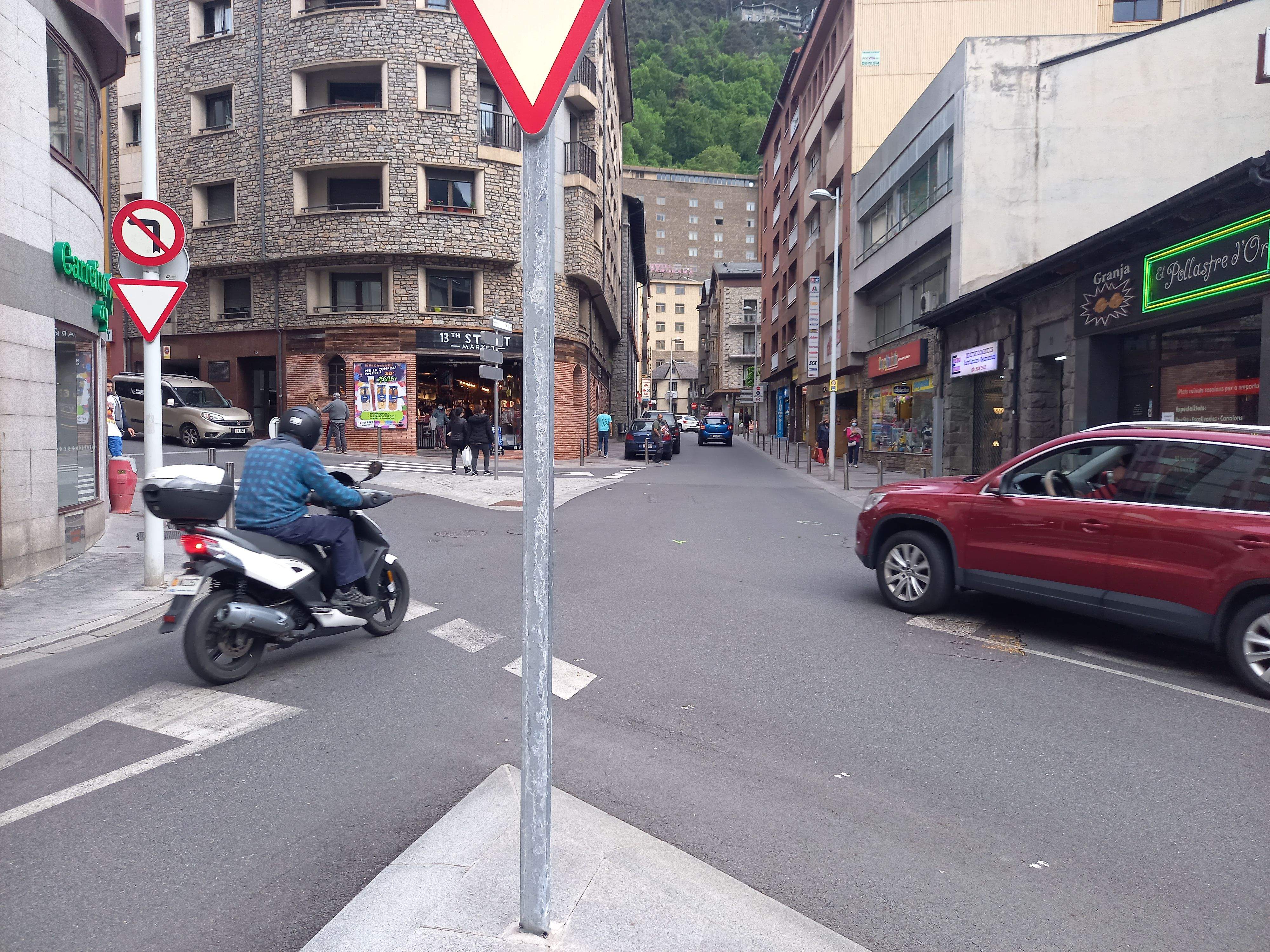 Una moto frena abans de superar la cruïlla, on encara es veuen restes al terra del darrer accident.