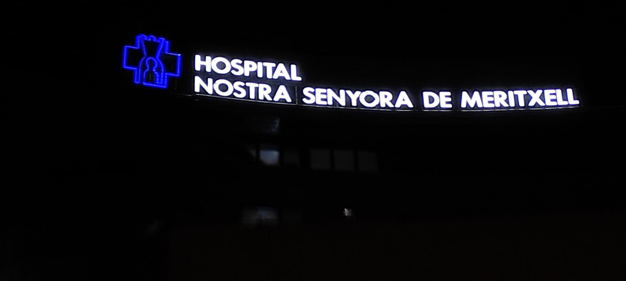 El rètol de l'hospital encès enmig de la nit.
