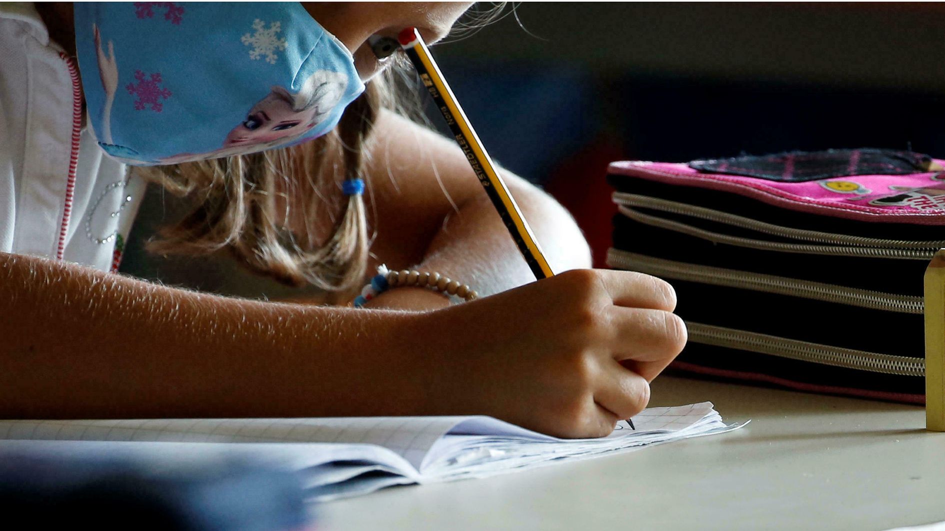 Una escolar amb mascareta fen treball a classe.