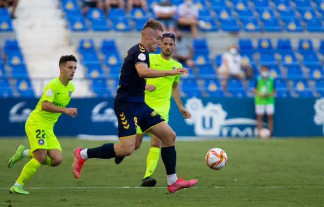 Manu Garrido condueix l'esfèrica sota la mirada de dos jugadors tricolors.