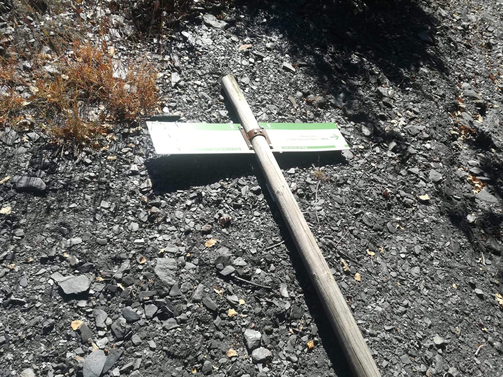 Un pal de senyalització al camí del Roc de l'Àliga a terra.
