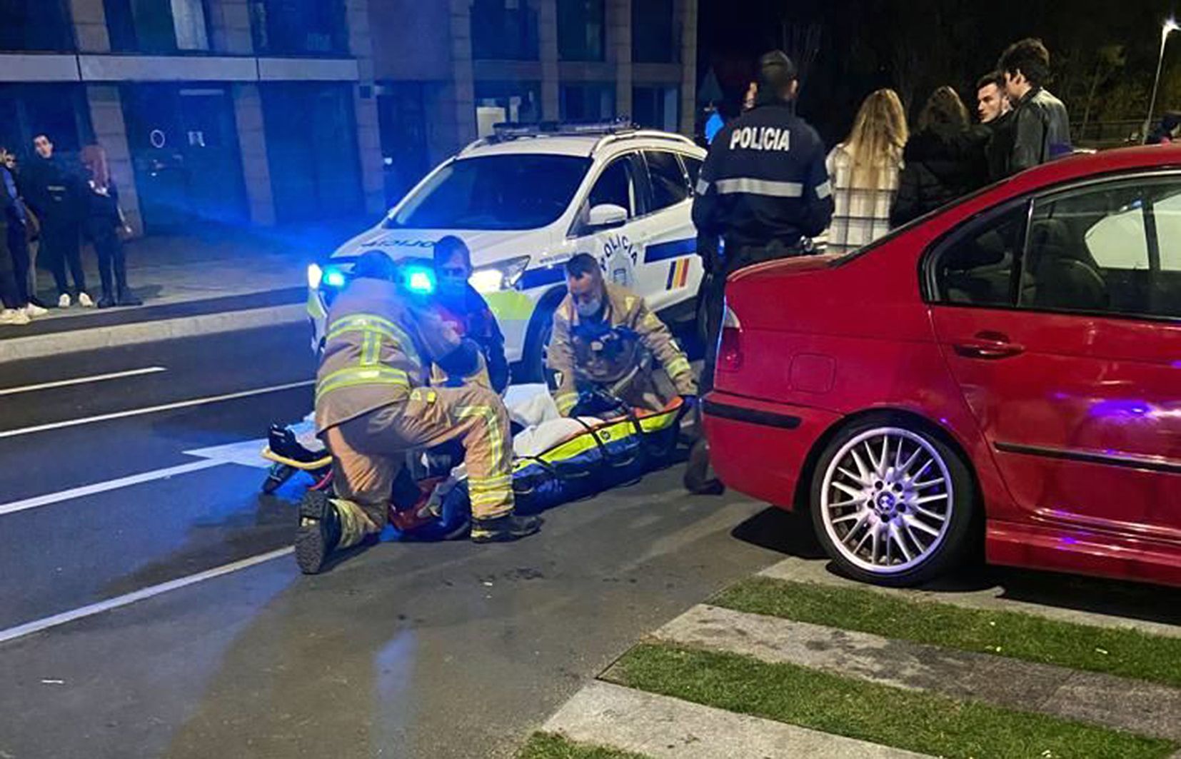 Agents dels bombers atenen la jove mentre policies parlen amb testimonis del fet.