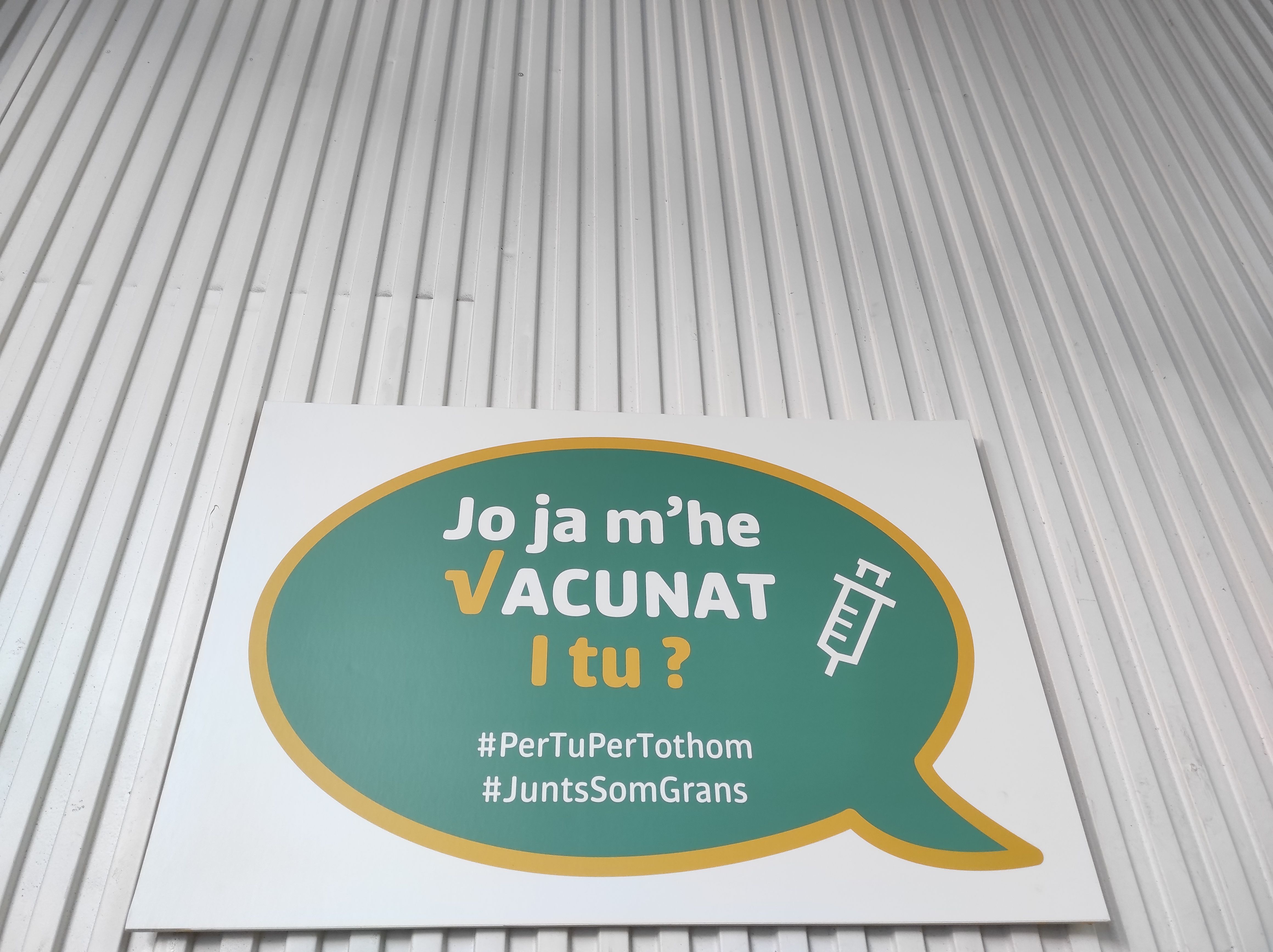 Un cartell que anima a vacunar-se al centre de l'antiga plaça de Braus.