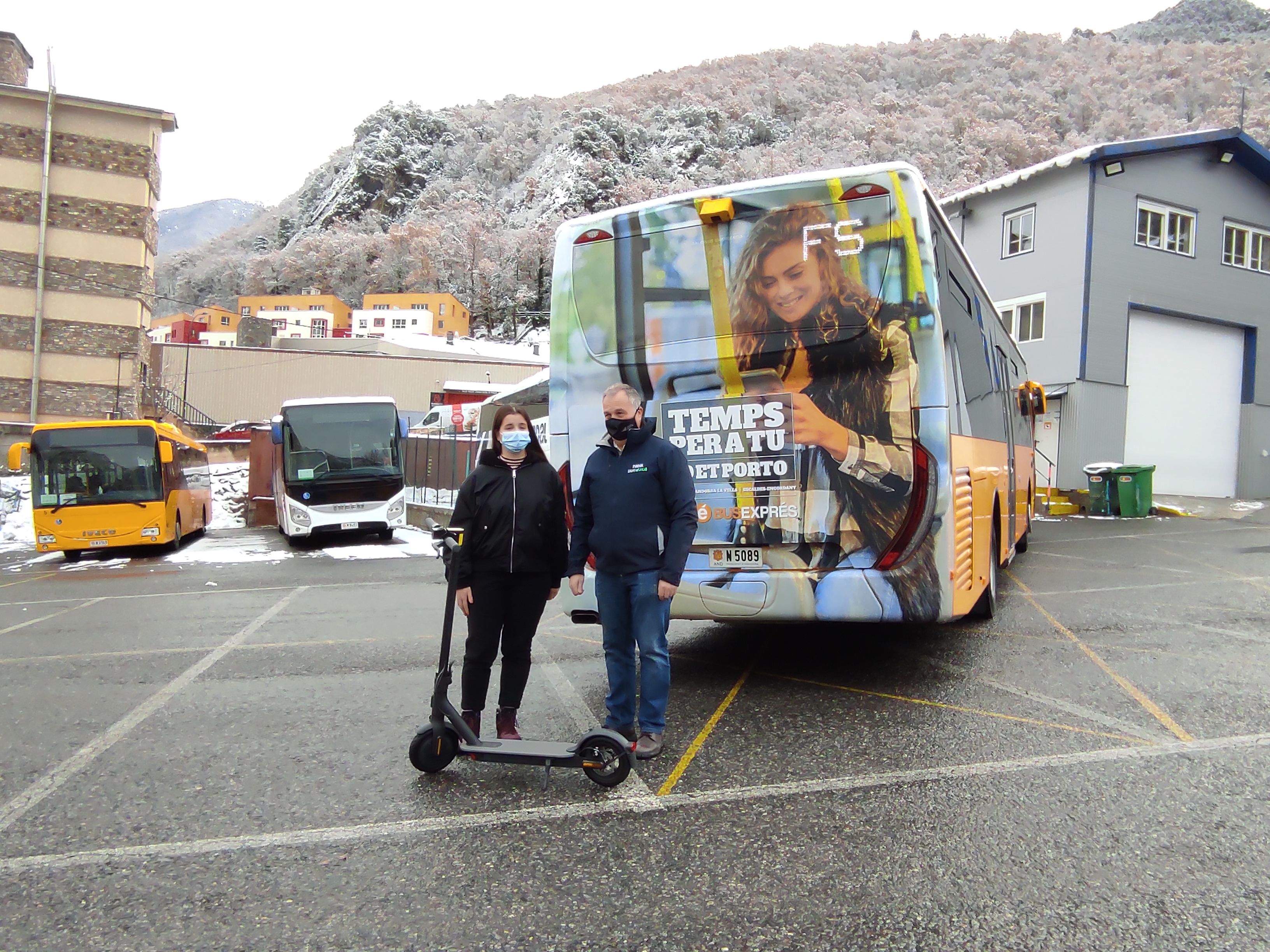 Bartumeu Gabriel amb la guanyadora d'un patinet elèctric per haver respost l'enquesta davant un bus amb el grafisme de la nova campanya. La portaveu del Sindicat, Rebeca Bonache.