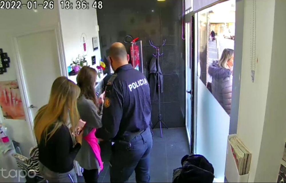 Un agent de policia parlant amb l'afectada en presència de la clienta en una captura de la gravació feta per la càmera de seguretat de l'establiment.