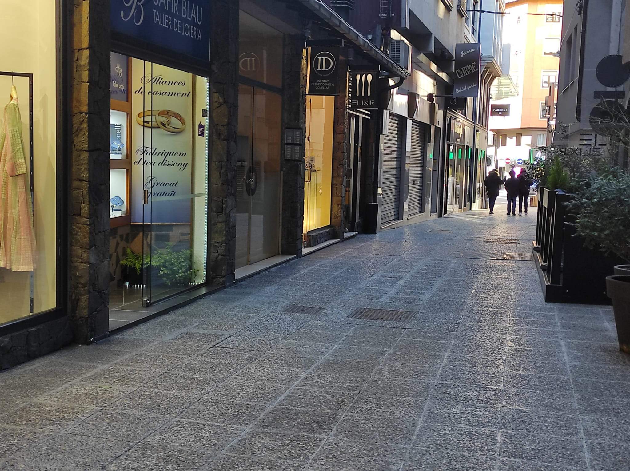 Tres investigadors de la policia marxen pel carrer del Roc dels Escolls amb la joieria afectada, en primer terme a l'esquerra.